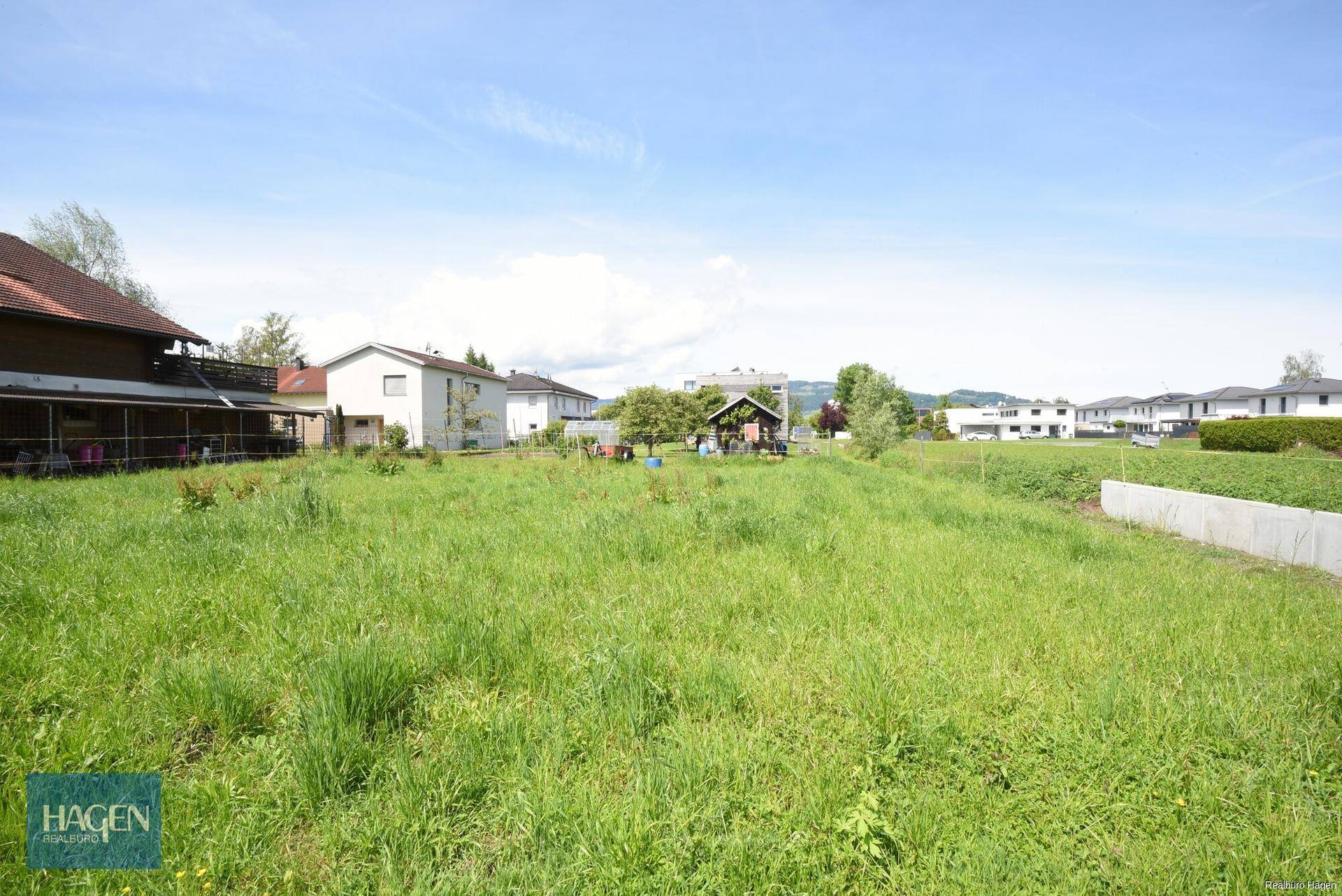 Großes, sonniges Gartengrundstück mit üppigem Gras und Blick auf die umliegenden Häuser und die Landschaft.