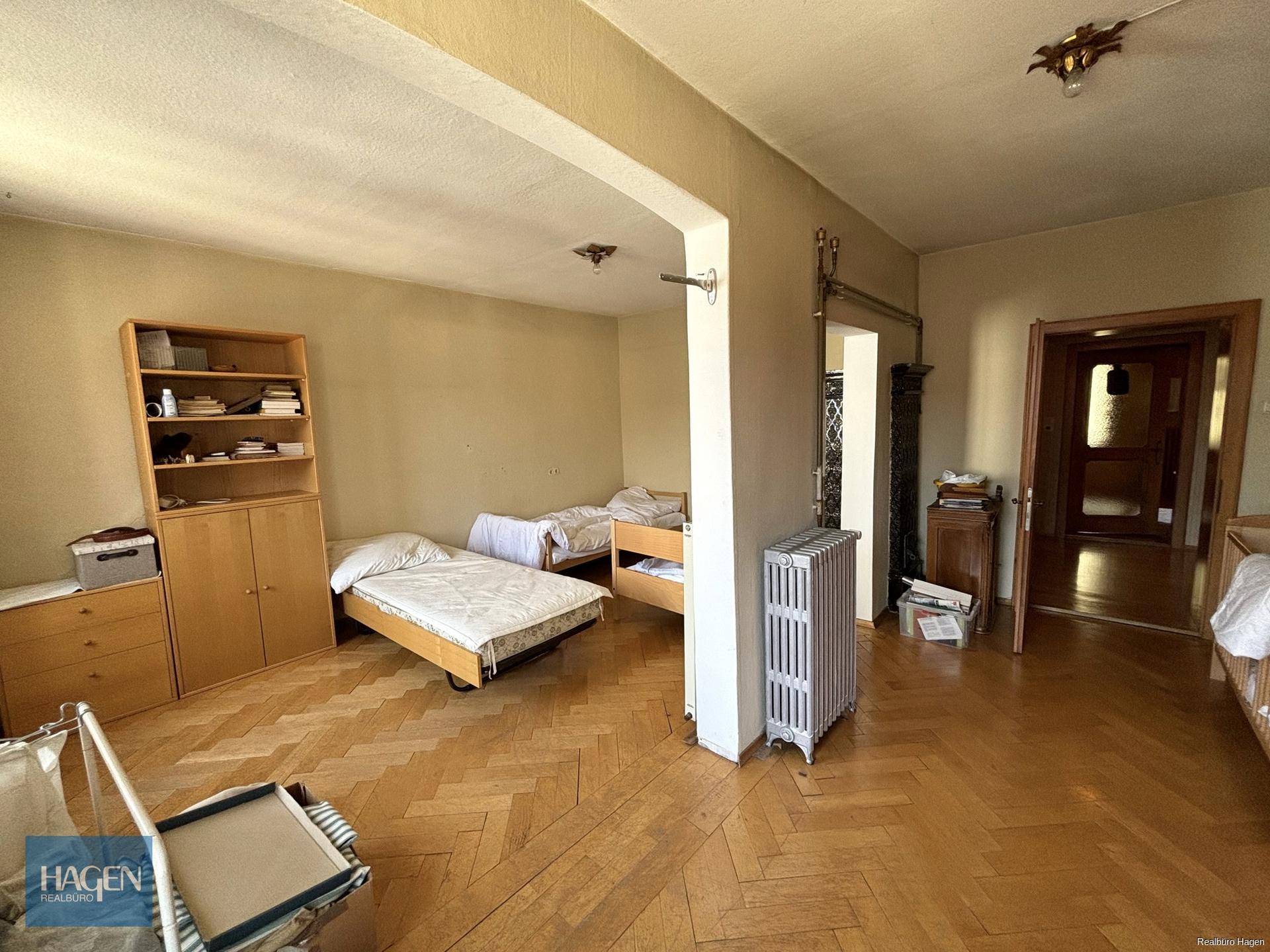 Geräumiges Schlafzimmer mit Parkettboden, zwei Betten und Heizkörper.