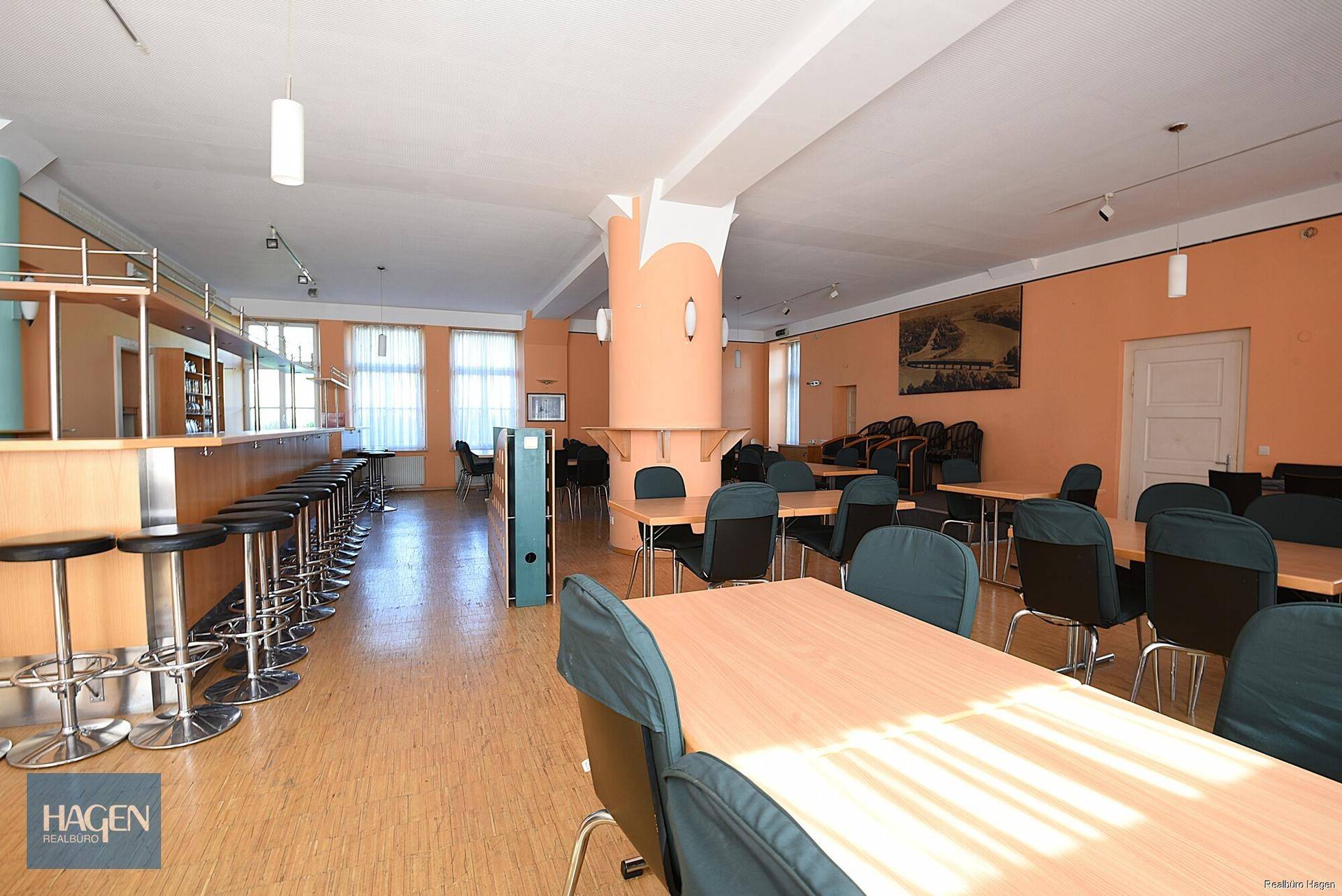 Großer Speisesaal oder Konferenzraum mit Holztischen, Stühlen und einer langen Bar mit Hockern.