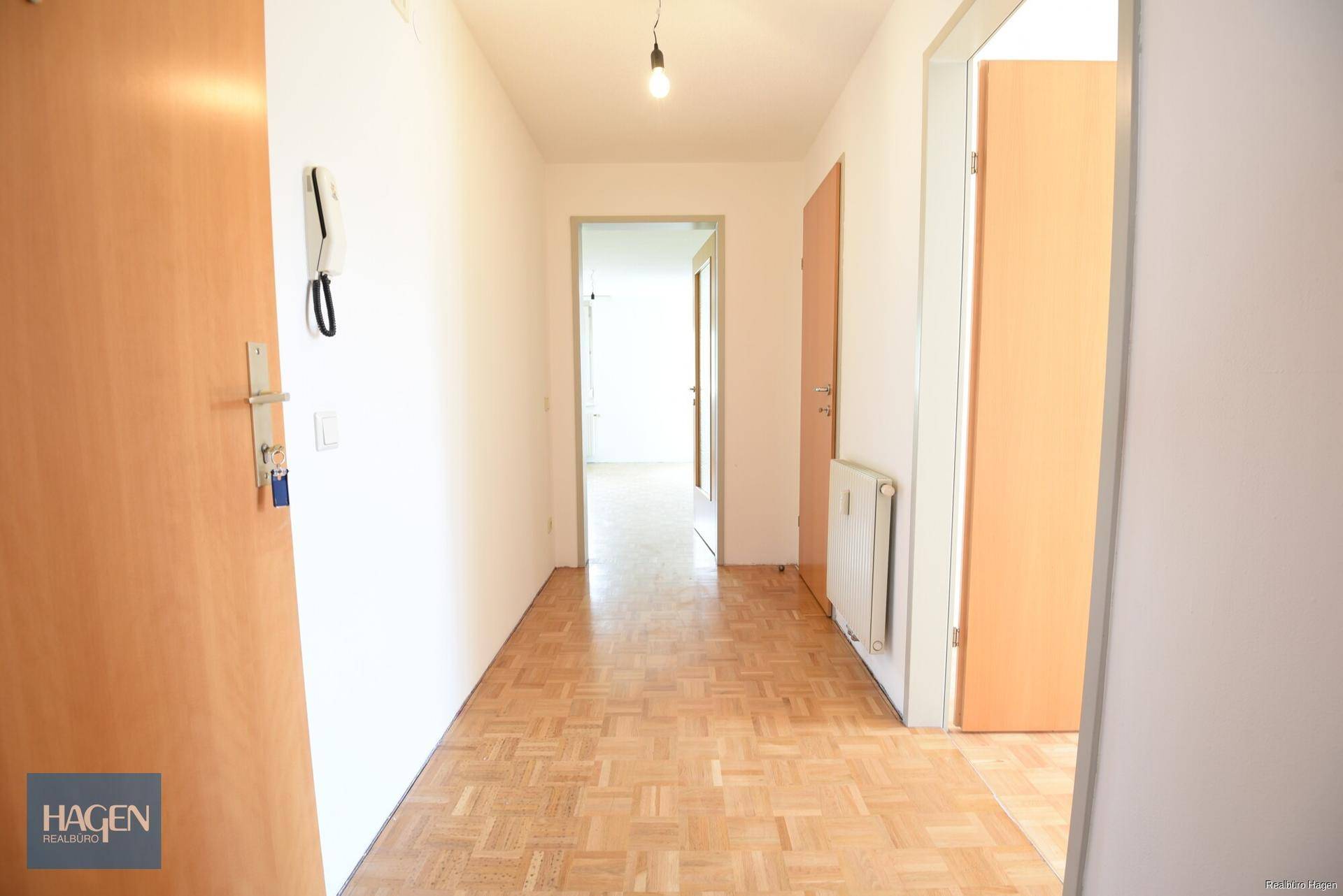 Heller Flur mit Parkettboden und Holztüren, der zu weiteren Räumen führt.