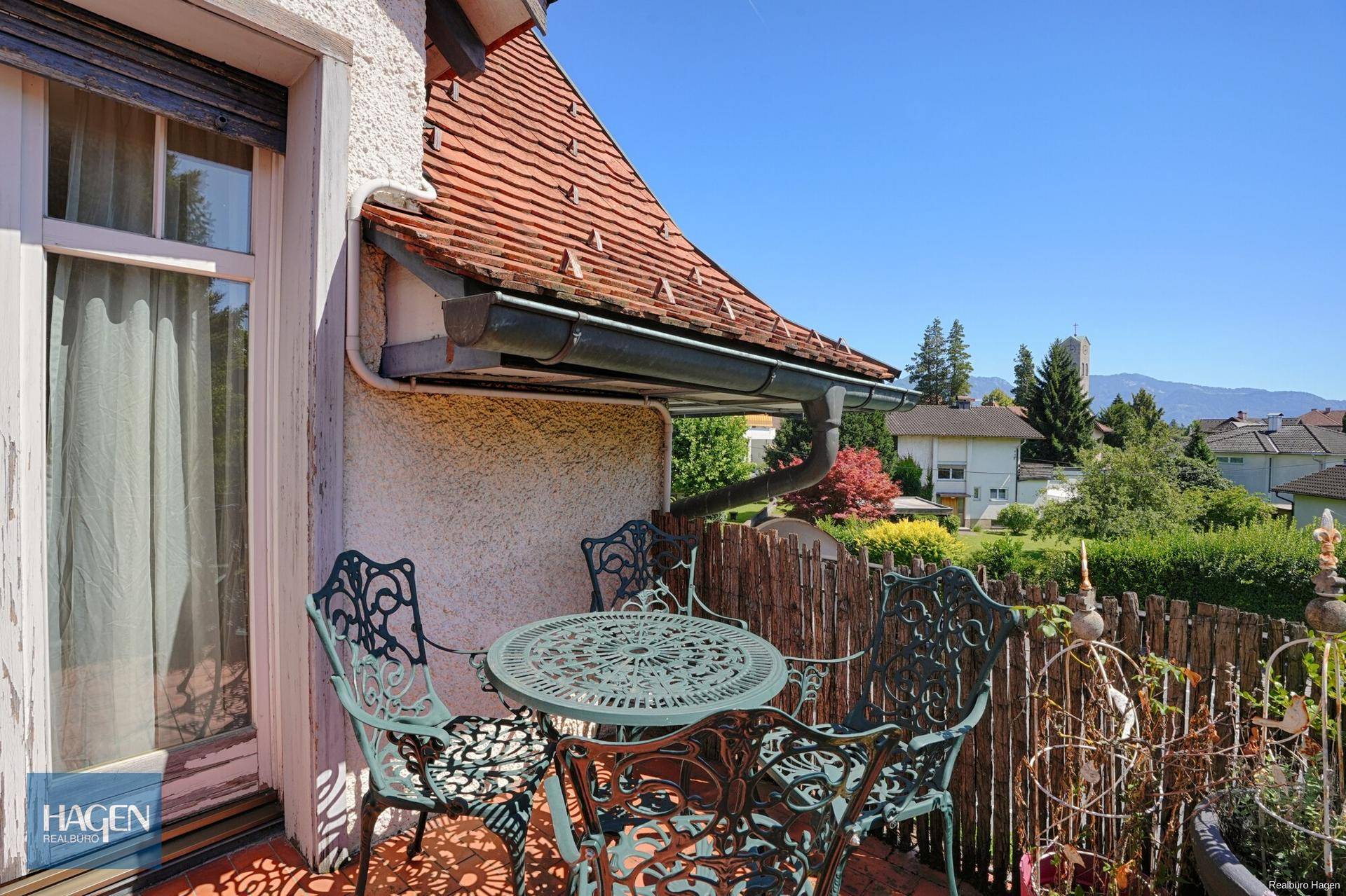 Sonniger Balkon mit schmiedeeisernen Möbeln und weitem Blick über die Umgebung.