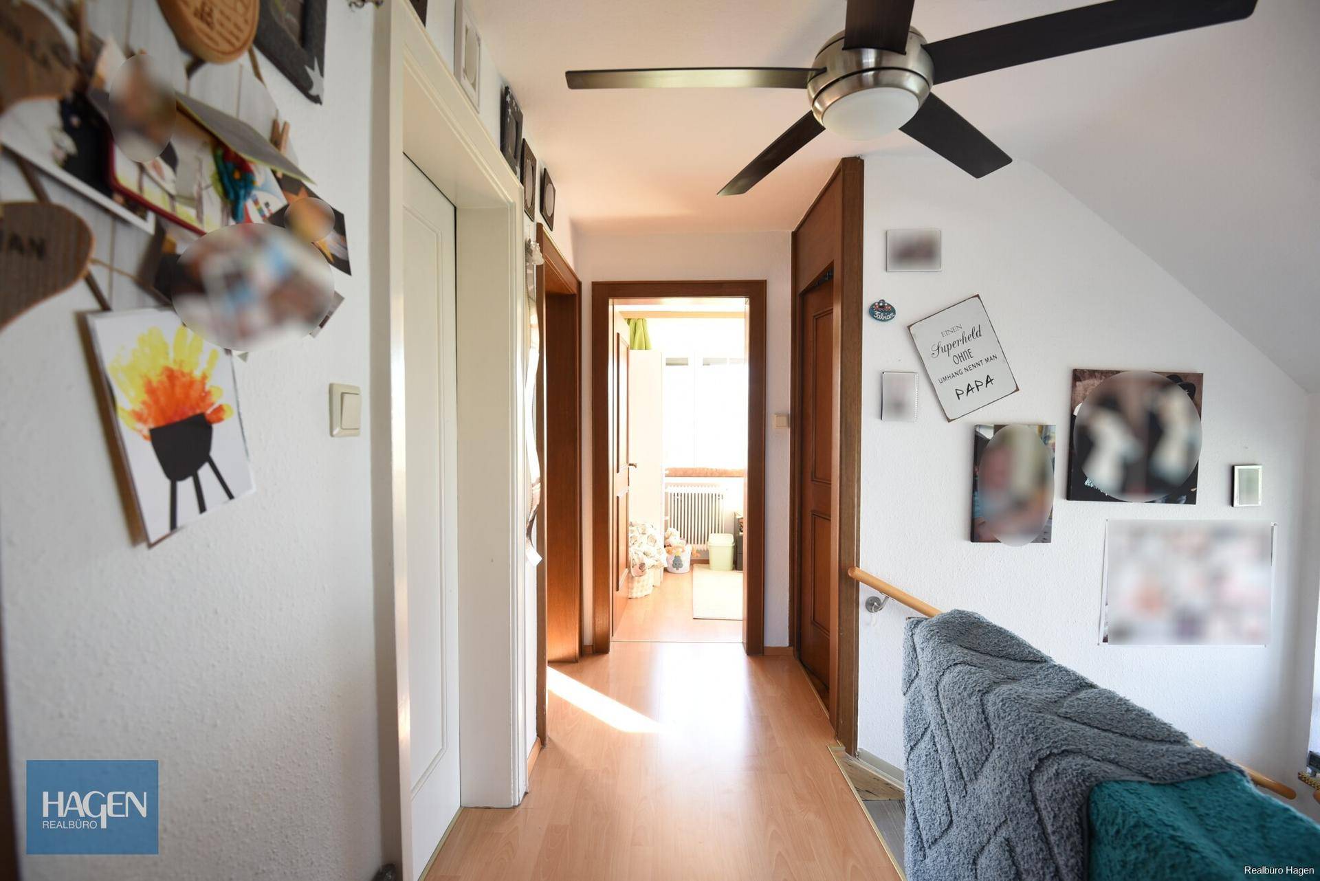 Heller Flur im Obergeschoss mit Laminatboden und Deckenventilator.