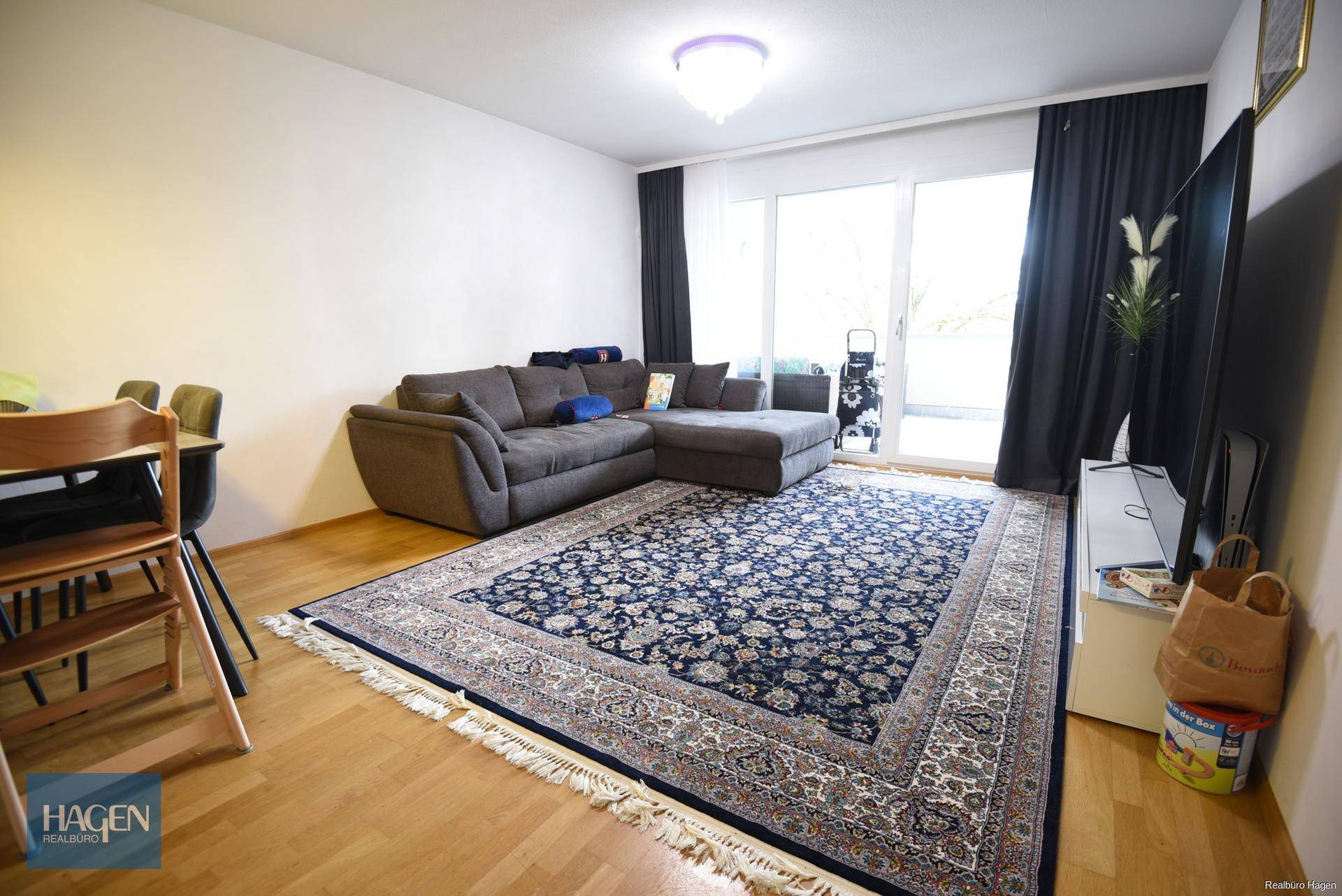 Geräumiges Wohnzimmer mit großem Ecksofa, Teppich und Zugang zur Terrasse durch eine Glasschiebetür.