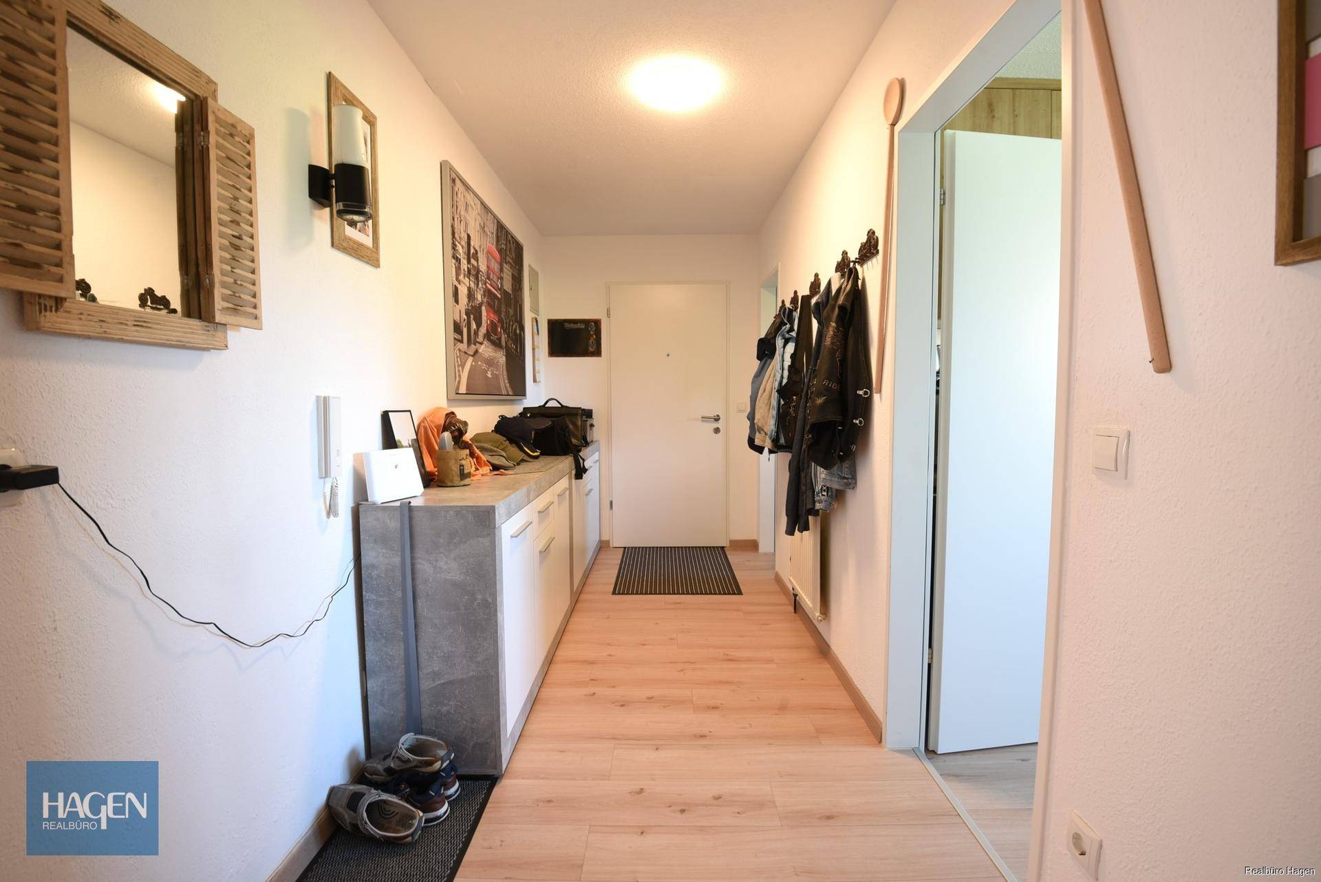 Heller Flur mit Garderobe, Konsole und Spiegel, führt zu weiteren Räumen der Wohnung.