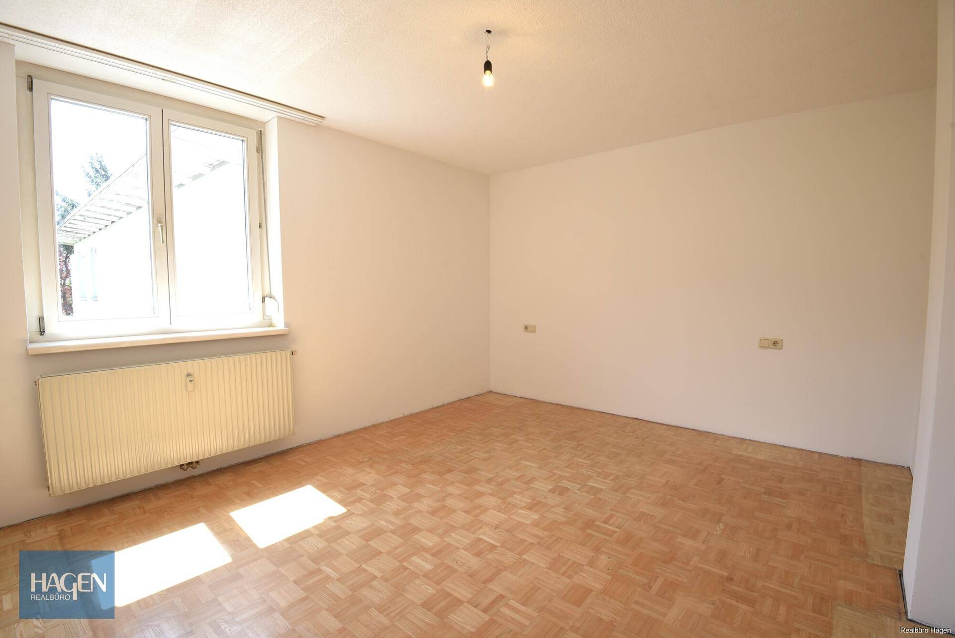 Heller Raum mit Parkettboden und großem Fenster, ideal als Schlaf- oder Kinderzimmer.