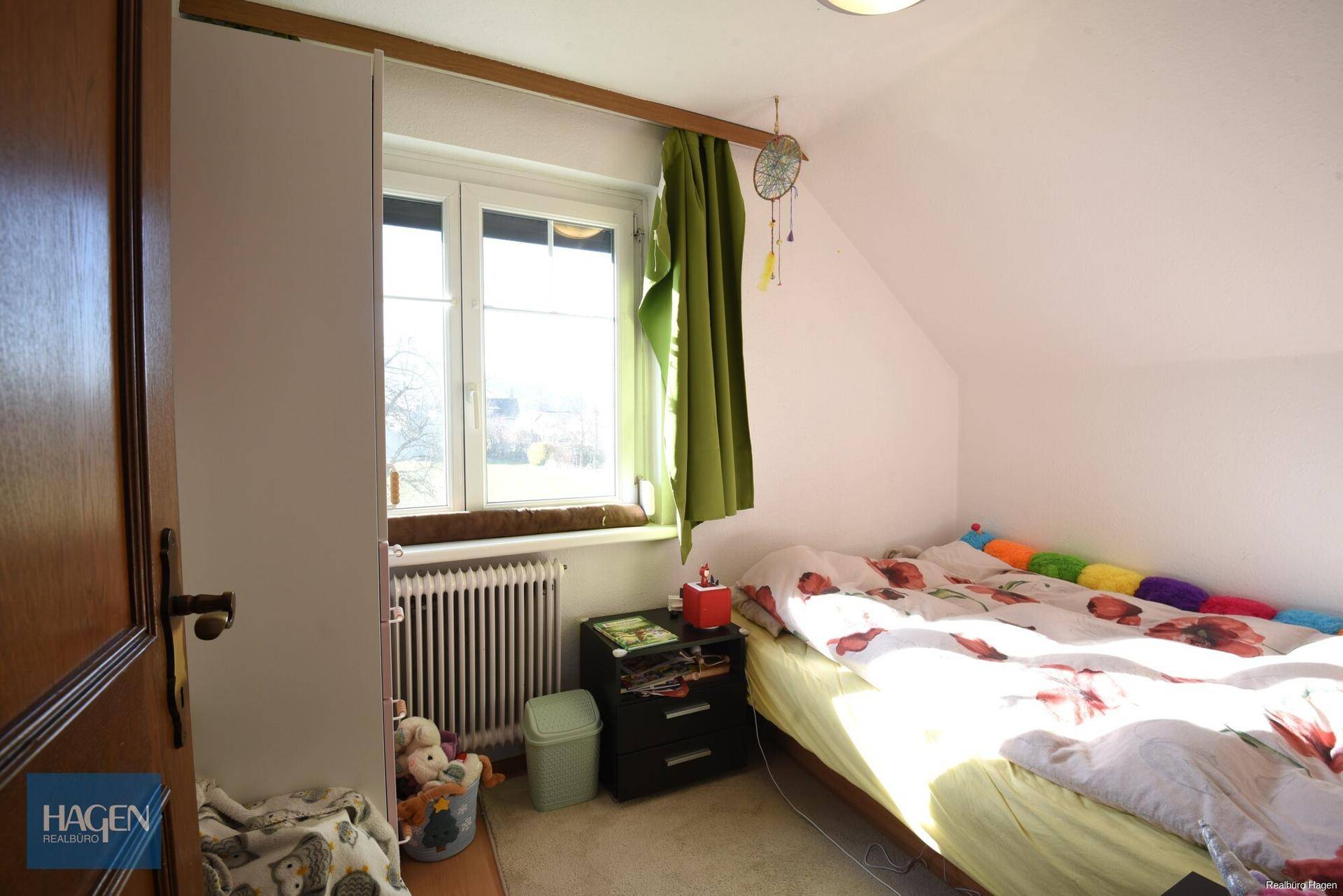 Helles Schlafzimmer im Dachgeschoss mit Schrägen, Laminatboden und Fenster.