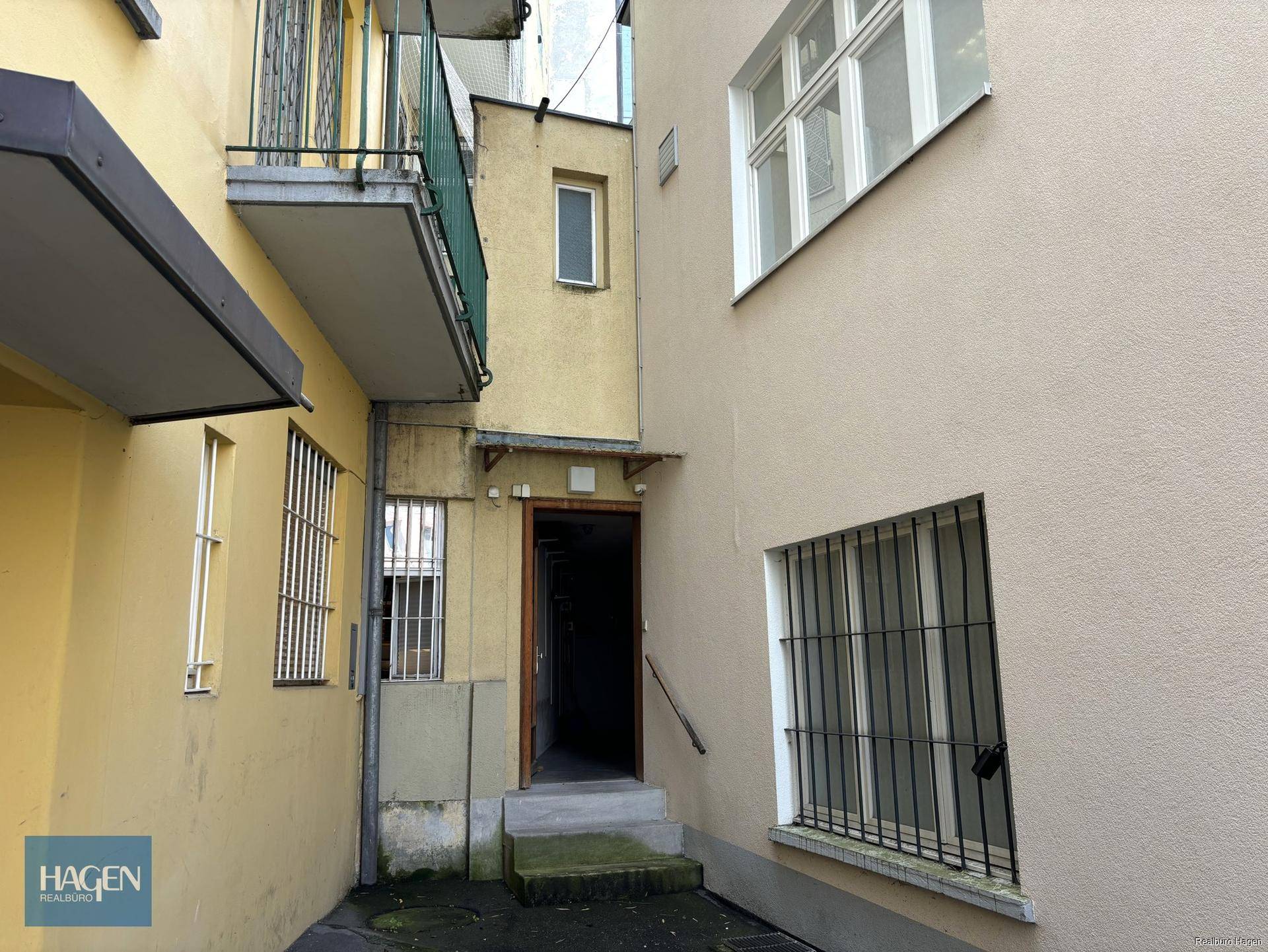 Hinterhofbereich zwischen Gebäuden mit Zugang zu einem Eingang und Balkonen.