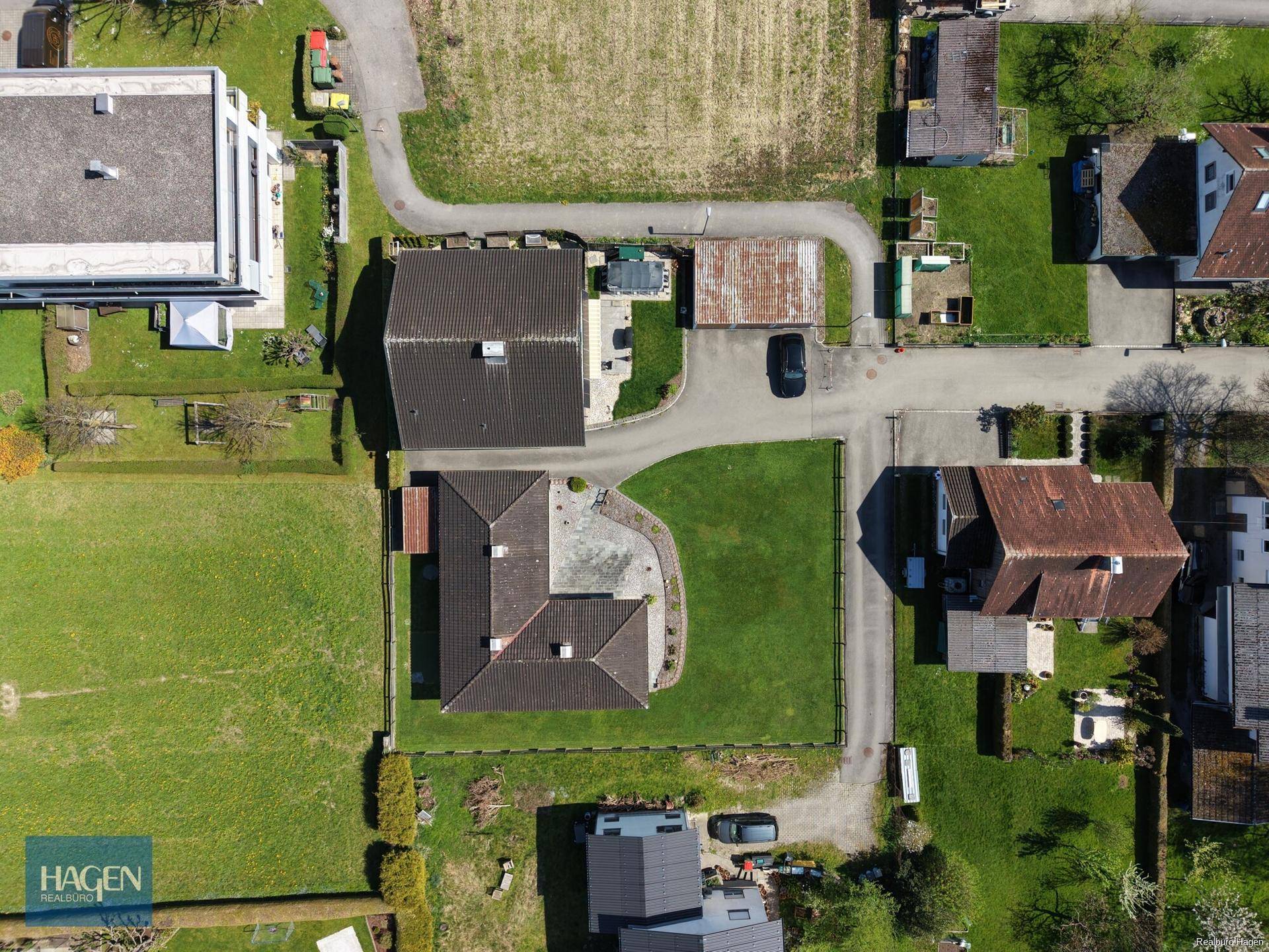Luftaufnahme eines Wohnhauses mit großem Garten, Zufahrt und angrenzenden Feldern.