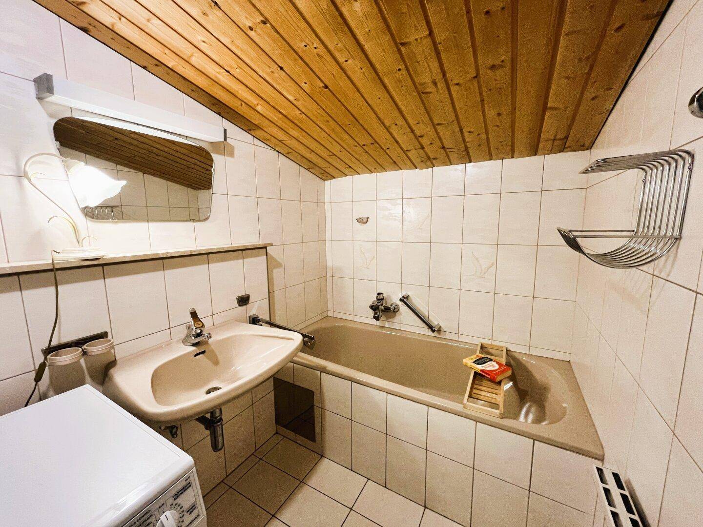 Badezimmer mit Badewanne, Waschbecken, Waschmaschinenanschluss und WC