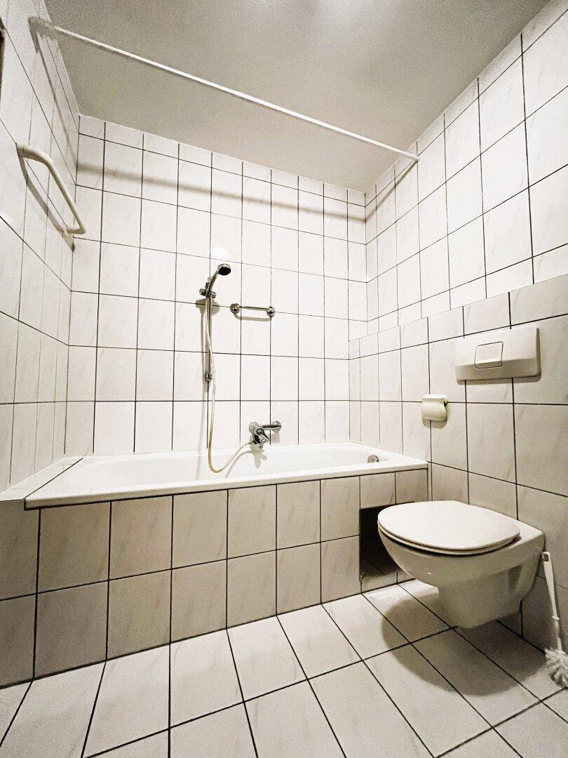 Badezimmer mit Badewanne, WC, Waschbecken und Waschmaschinenanschluss