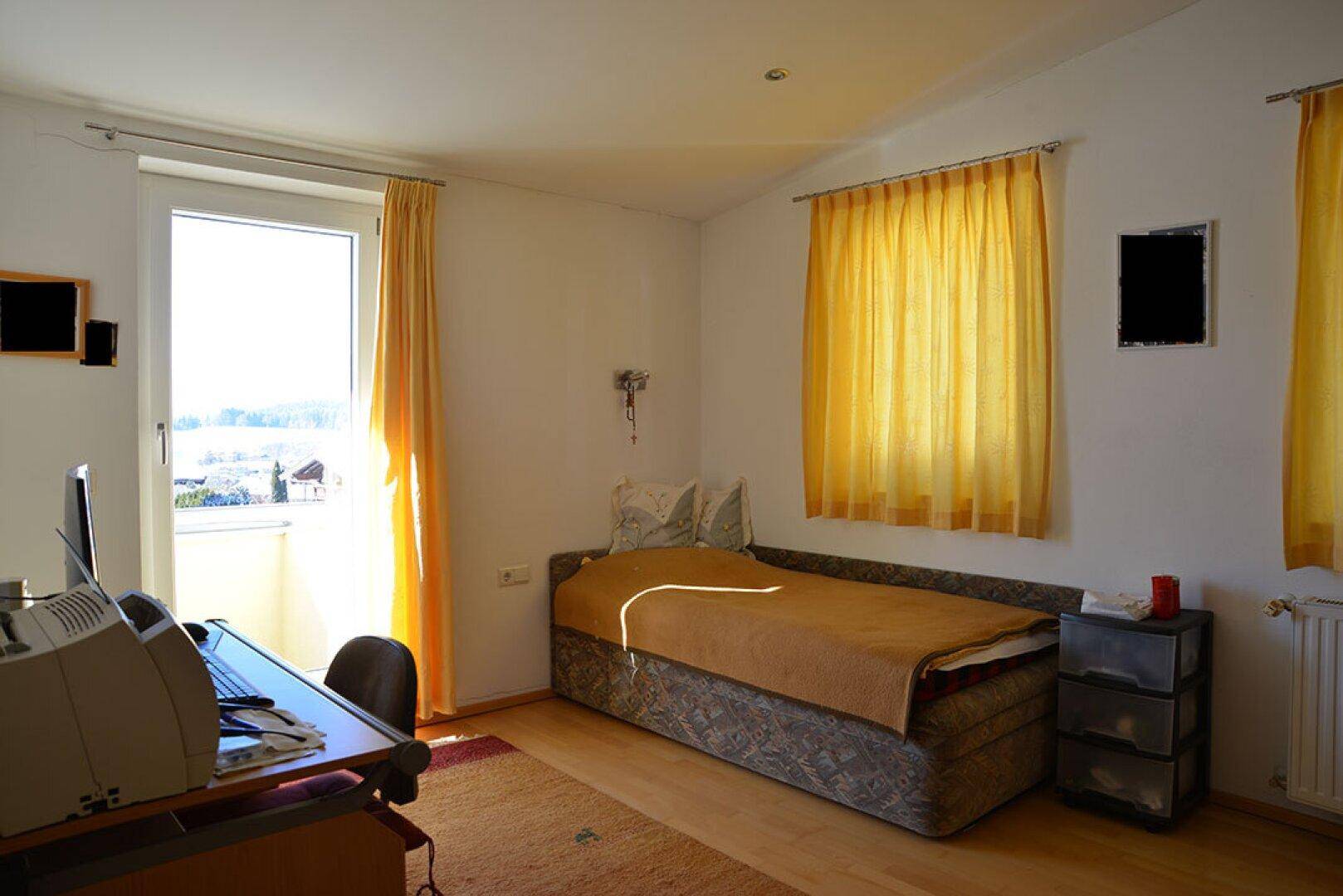 Helles Schlafzimmer oder Büro mit Einzelbett, Schreibtisch und Fenster mit weitem Ausblick.