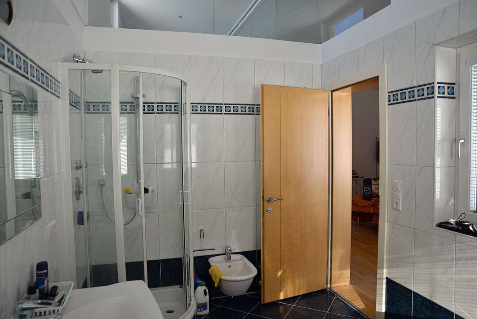 Badezimmer mit Duschkabine, Bidet und weiß-blauen Fliesen, die ein frisches Ambiente schaffen.