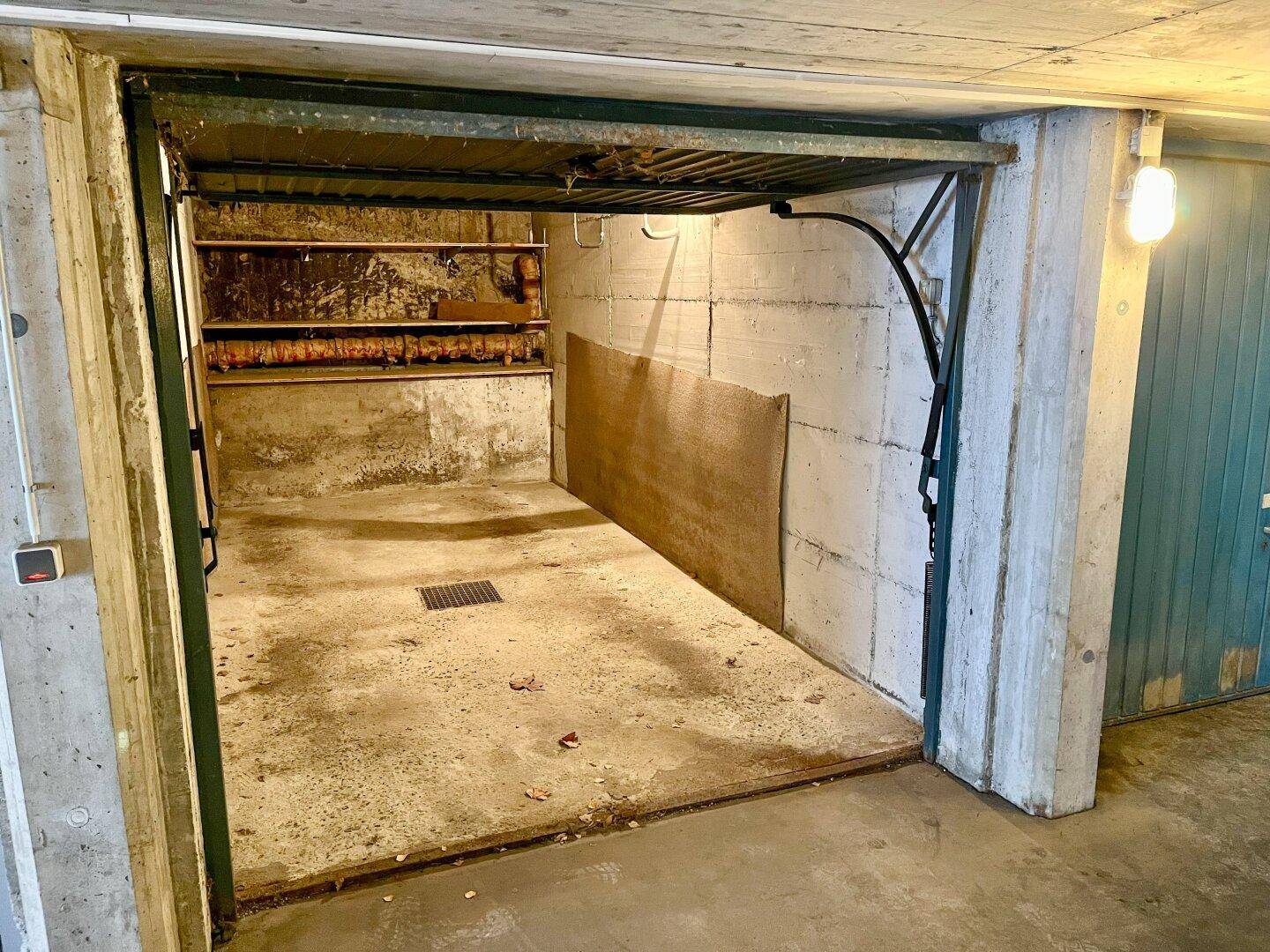Offene Einzelgarage mit Betonwänden und -boden, bietet Platz für ein Fahrzeug.