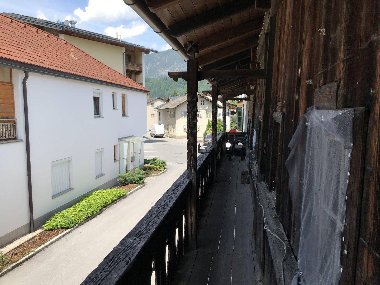 Langer Holzbalkon mit Blick auf die Straße und die gegenüberliegenden Gebäude.