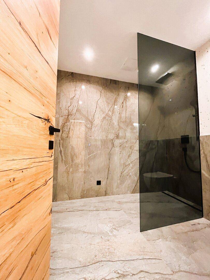 Modernes Badezimmer mit begehbarer Dusche und eleganten Marmorfliesen.