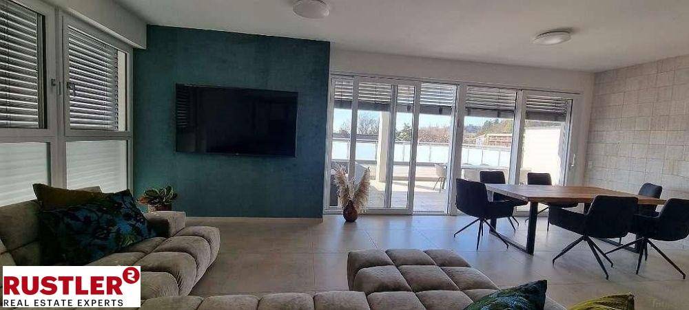 Moderner Wohn-Essbereich mit dunkler Akzentwand, großem Fernseher und Zugang zur Terrasse.