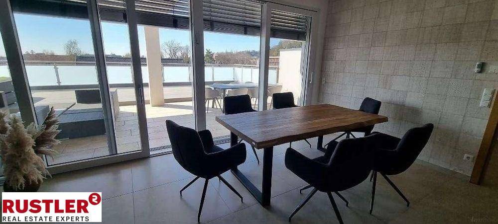 Heller Essbereich mit Holztisch und schwarzen Stühlen, direktem Zugang zur großen Außenterrasse.