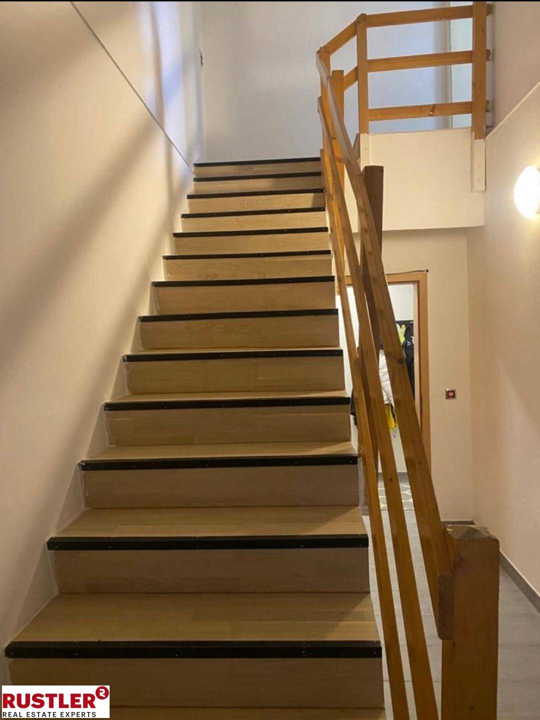 Holztreppe mit Geländer verbindet die Stockwerke des Hauses.