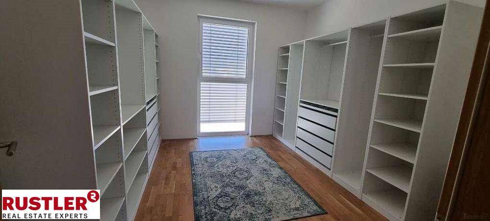 Geräumiger begehbarer Kleiderschrank mit vielen Regalen und Schubladen, ausgestattet mit Holzfußboden.