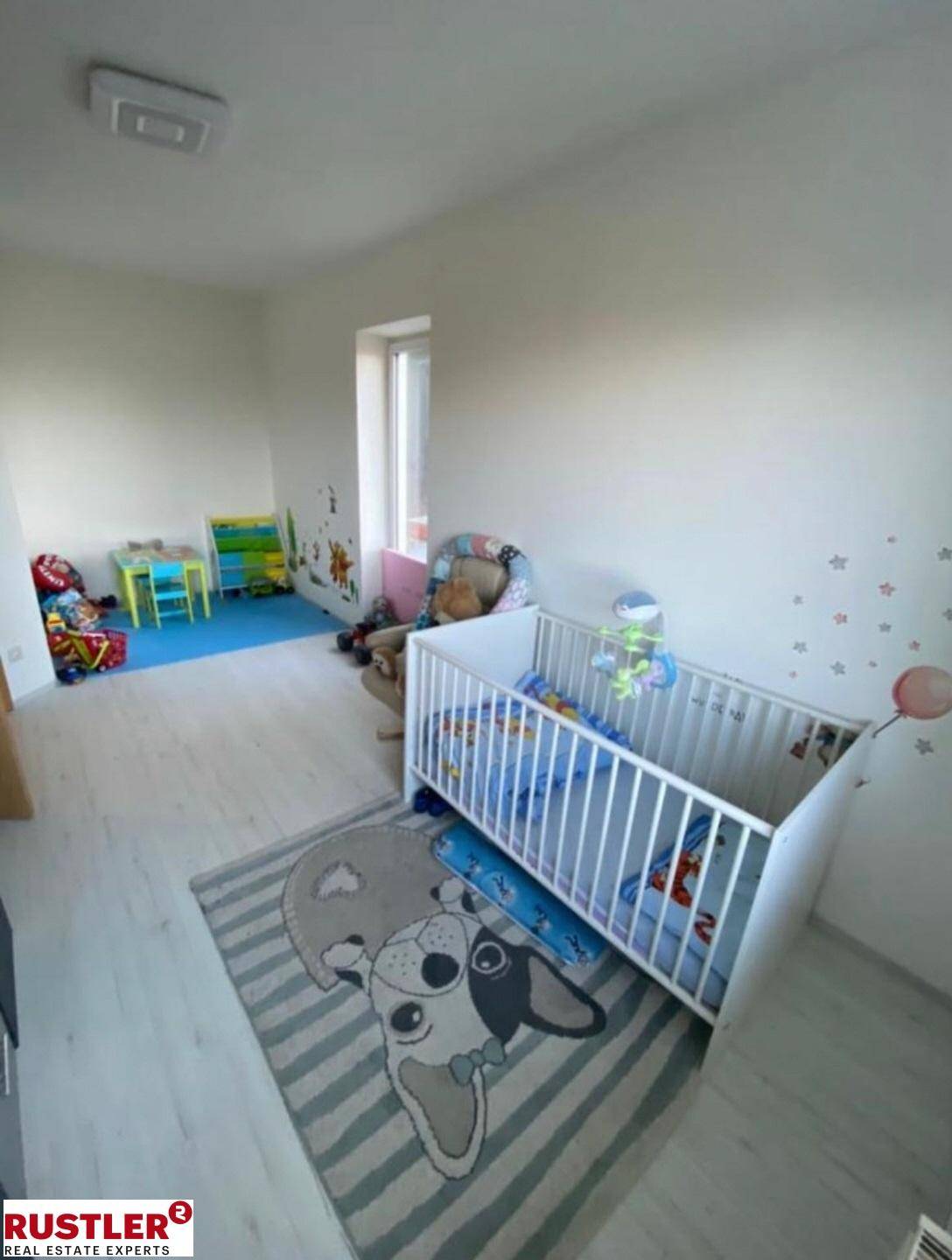 Kinderzimmer mit Babybett, Spielbereich und hellem Laminatboden.