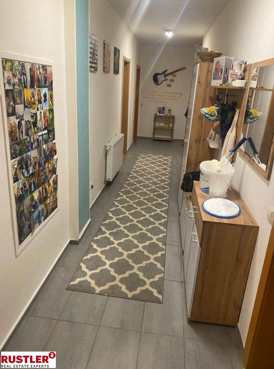 Langer Flur mit Fliesenboden, Garderobe und dekorativen Elementen.