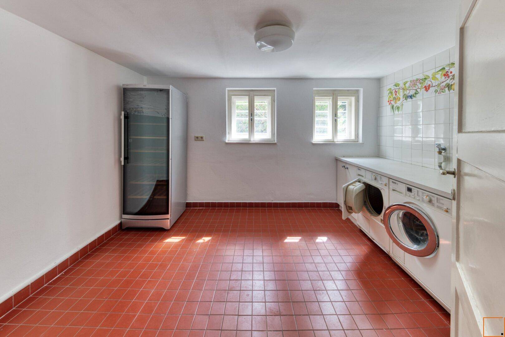 Hauswirtschaftsraum mit Waschmaschine, Trockner und praktischem Fliesenboden.