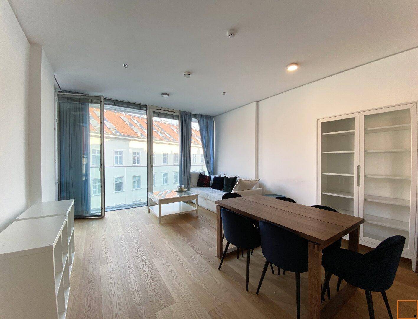 Heller Wohn-Essbereich mit Holzboden, Esstisch und großen Fenstern mit Stadtblick.
