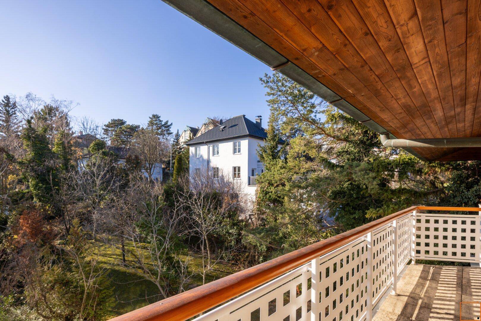 Balkon mit Blick auf ein charmantes Haus und die umliegende grüne Landschaft.