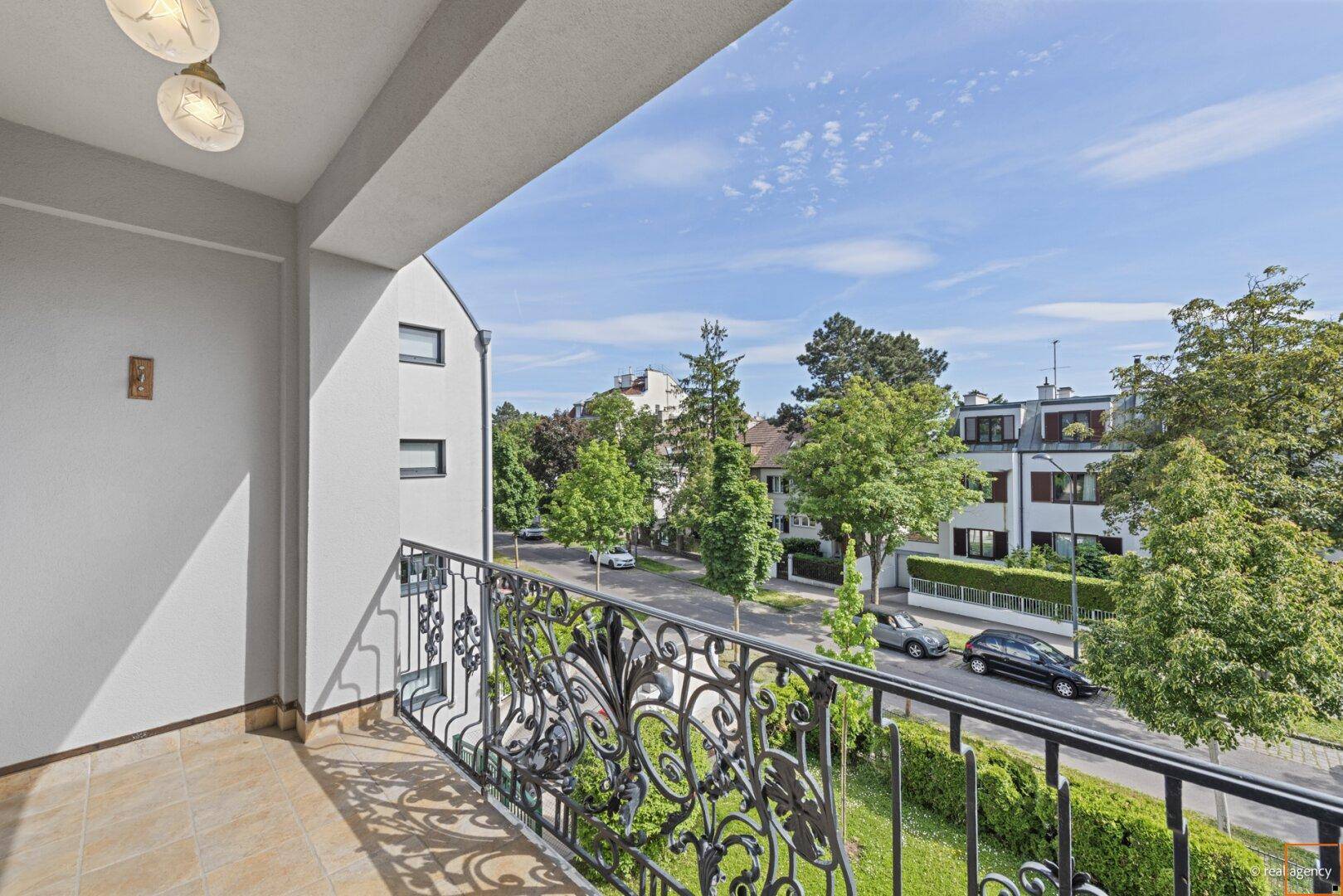 Blick vom Balkon mit Fliesenboden auf die Straße und die umliegende Wohnbebauung.