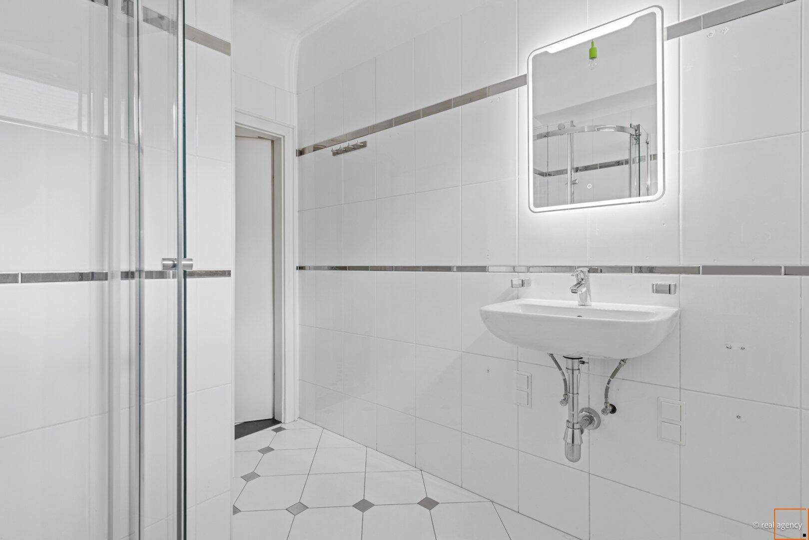 Modernes Badezimmer mit weißen Fliesen, Einzelwaschbecken und einer begehbaren Dusche mit Glaswand.