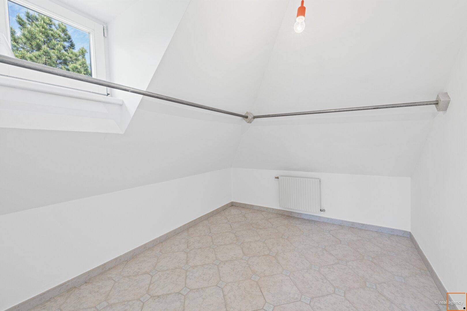 Kleiner Raum mit Fliesenboden, Dachschräge und Fenster, geeignet als Abstellraum oder kleines Arbeitszimmer.