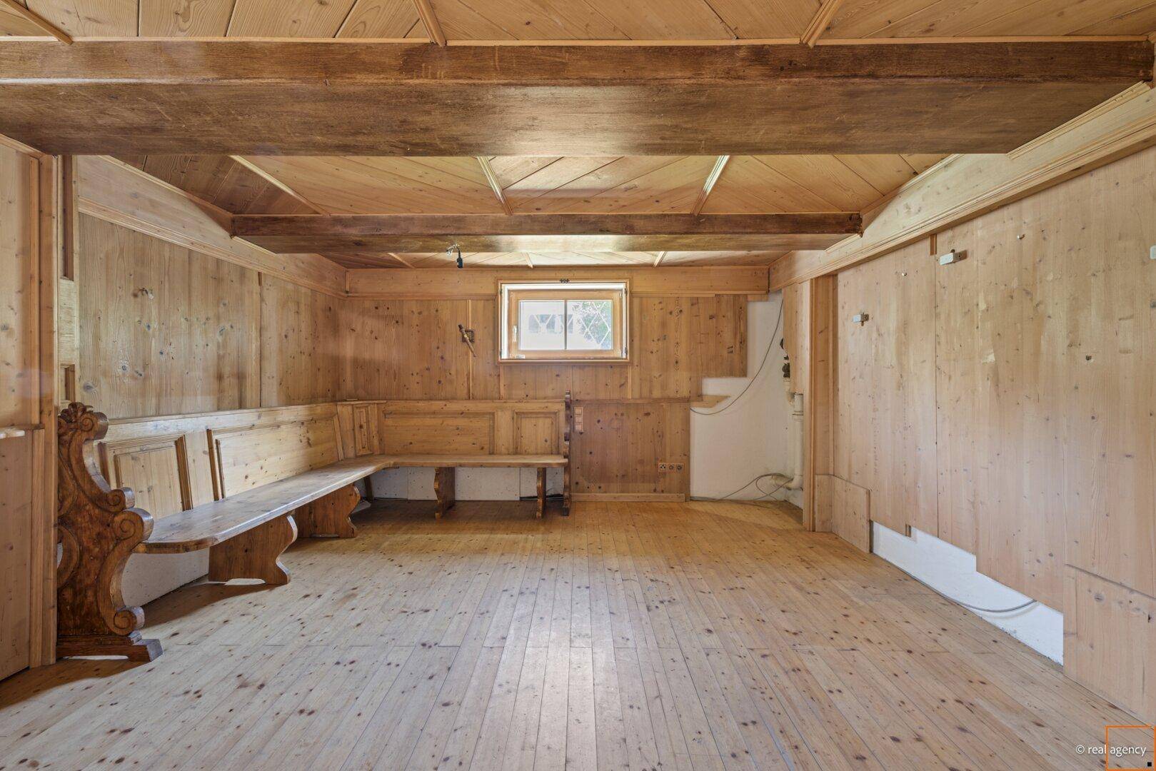 Traditioneller Raum mit Holzböden, Holzvertäfelung an Wänden und Decke sowie eingebauten Holzbänken.