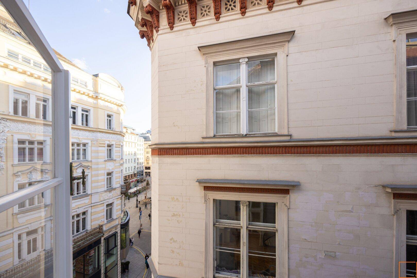 Detailansicht der historischen Fassade eines Gebäudes mit Fenstern und Blick auf die Straße.