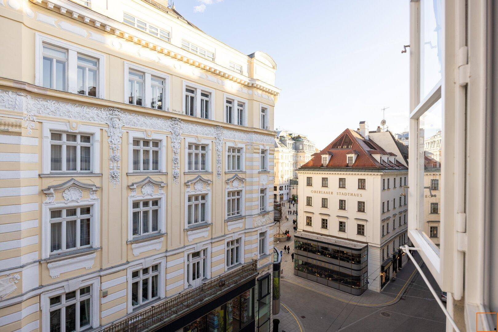 Blick aus dem Fenster auf die historische Stadtarchitektur und belebte Straße.