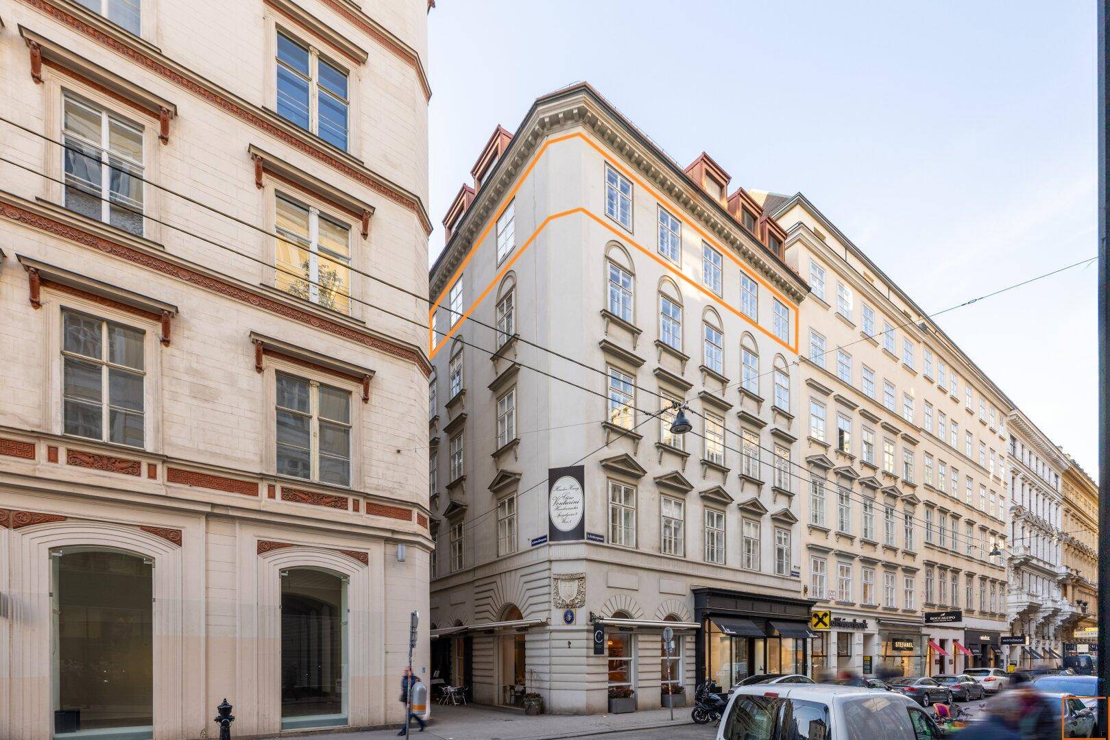 Historisches Eckgebäude in der Stadt mit markanter Architektur und Geschäften im Erdgeschoss.