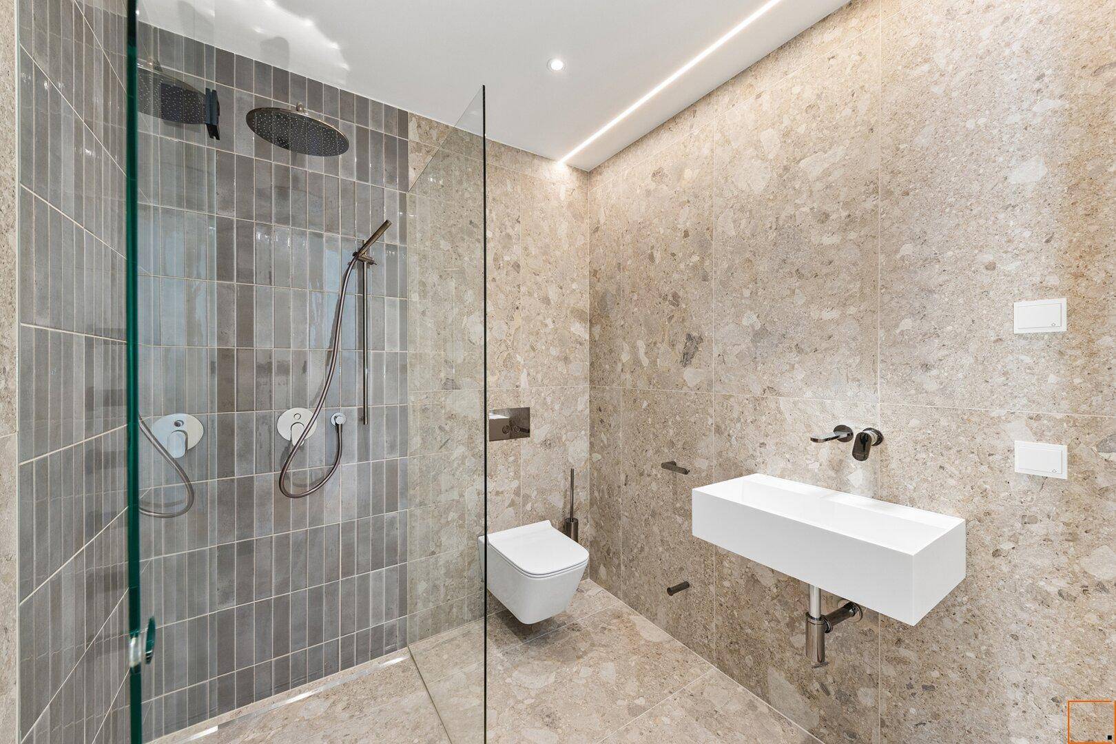 Modernes Badezimmer mit begehbarer Dusche, Wand-WC und eleganten Fliesen an Wänden und Boden.