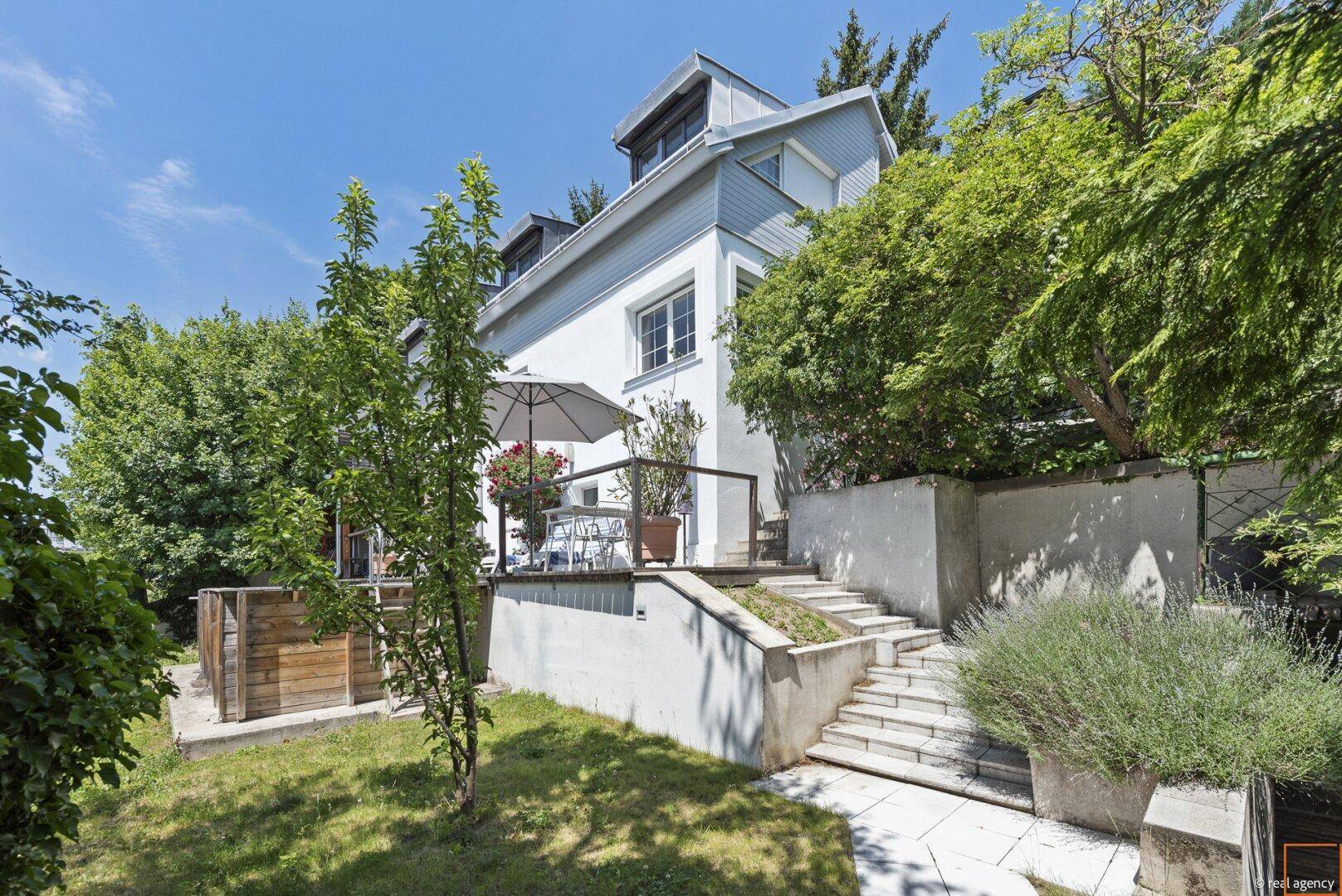 Gartenbereich mit Treppe zur Terrasse und Blick auf die weiße Hausfassade.