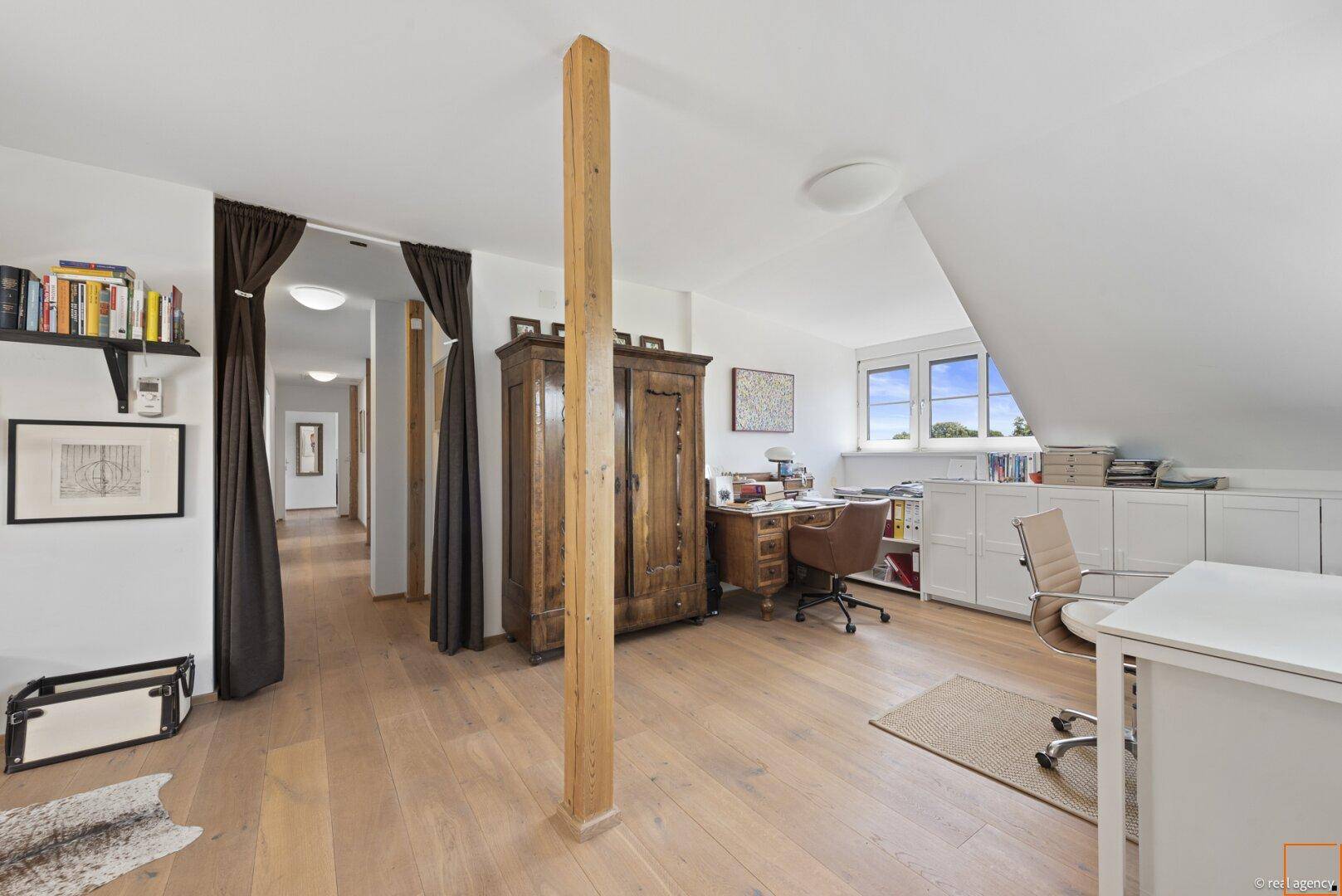 Geräumiges Dachgeschosszimmer als Büro mit Holzboden und viel Stauraum.