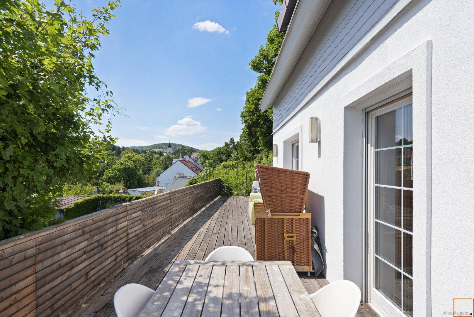 Lange Holzterrasse mit Essbereich und weitem Blick über die Umgebung.