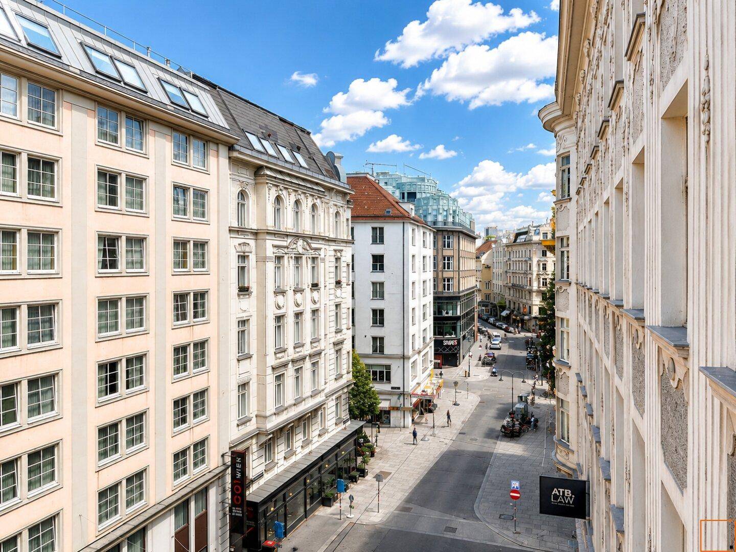 Panoramablick auf eine belebte Stadtstraße mit historischen Gebäuden und blauem Himmel.