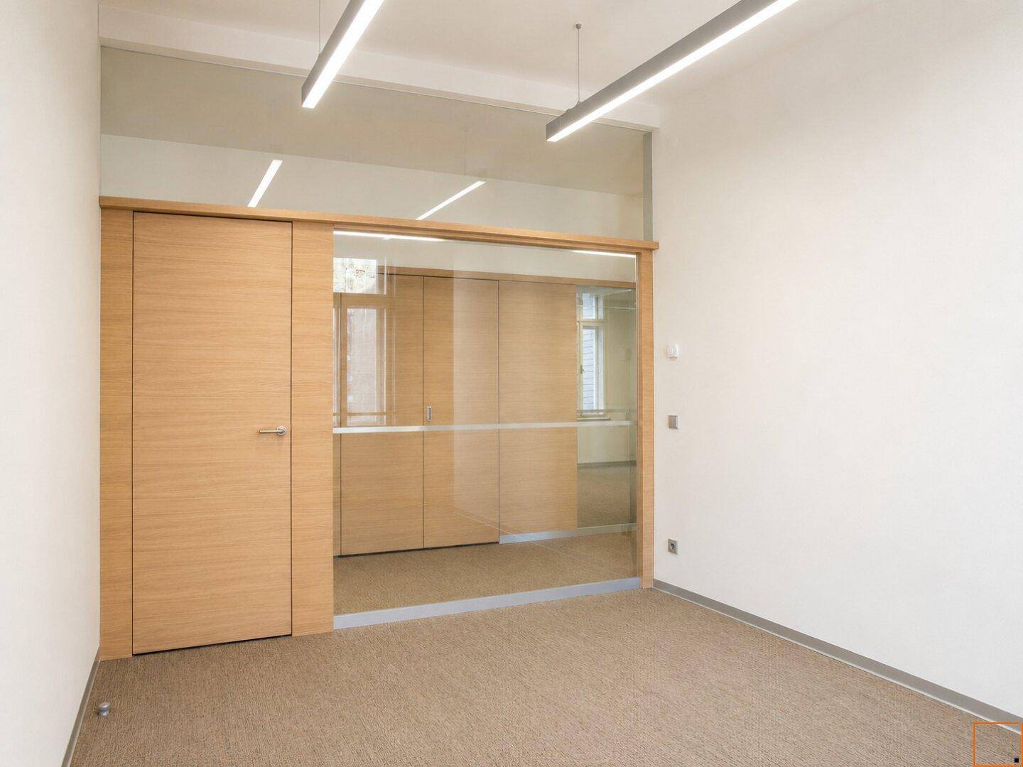 Moderner Büroraum mit Glastrennwänden und Holztüren, die eine flexible Raumgestaltung ermöglichen.