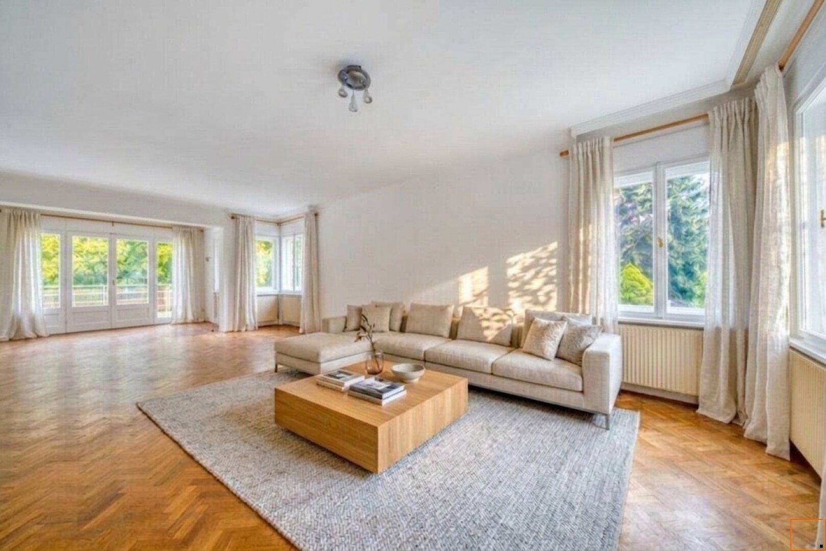 Gemütliches Wohnzimmer mit modernem Sofa, Teppich und hellem Fischgrätparkett.