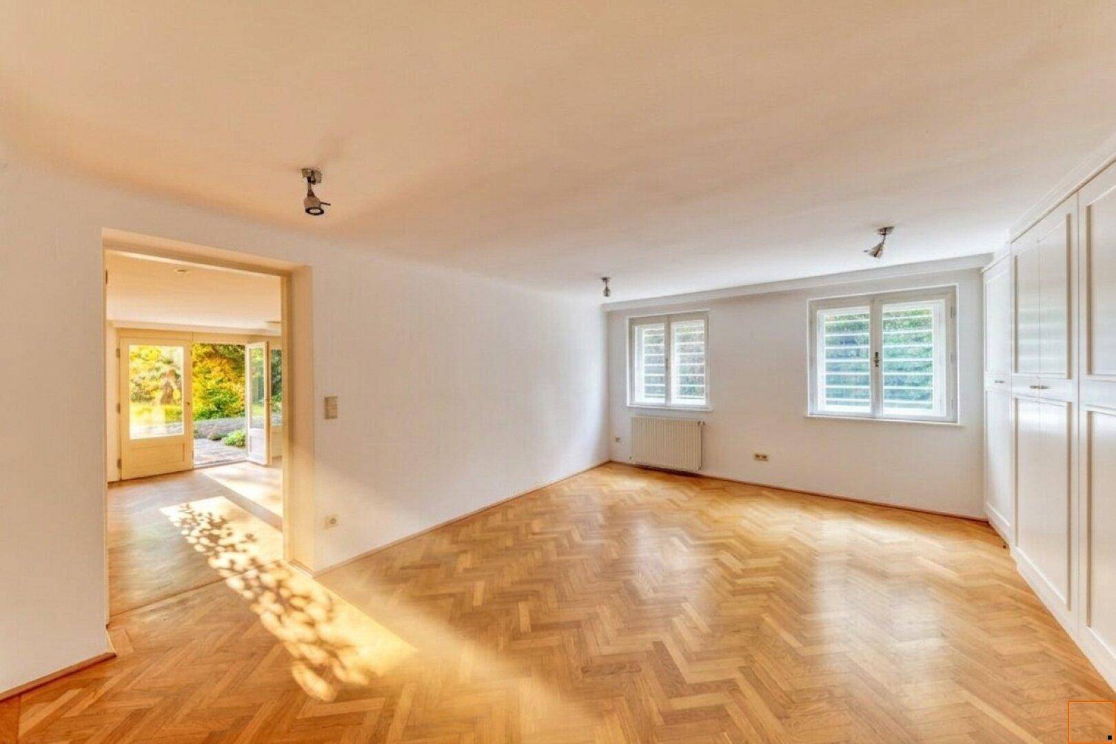 Helles Zimmer mit Fischgrätparkett, Einbauschränken und Blick in den Garten.
