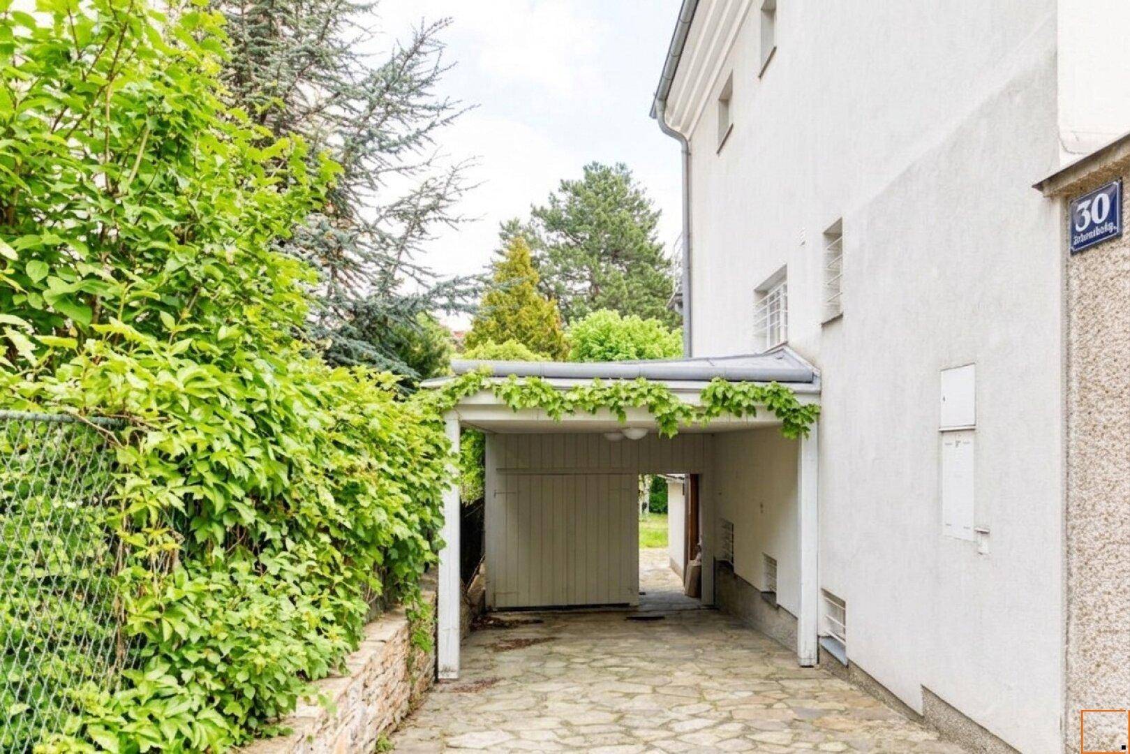 Überdachter Stellplatz (Carport) neben dem Haus mit Zufahrt.