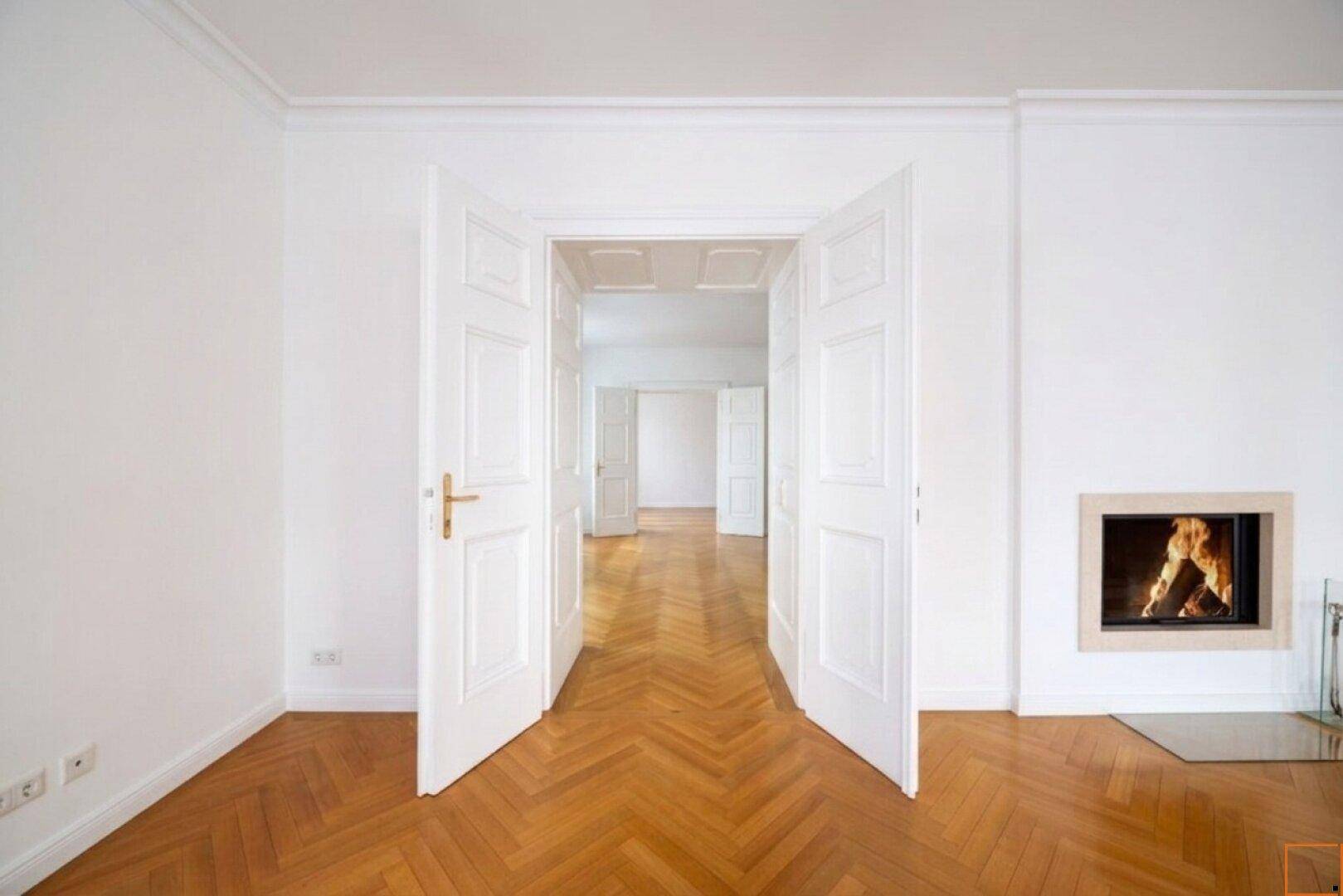 Detailansicht des Kamins mit brennendem Feuer und eleganten Doppeltüren, die in den nächsten Raum führen.