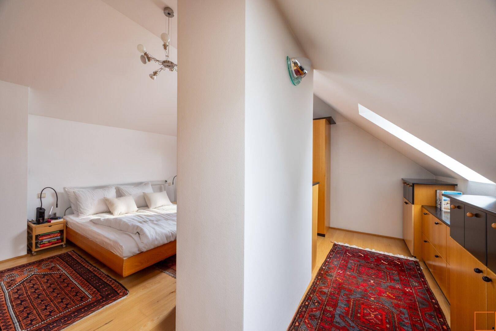 Offener Bereich mit Schlafzimmer und kleiner Küchenzeile unter schrägen Dachfenstern.