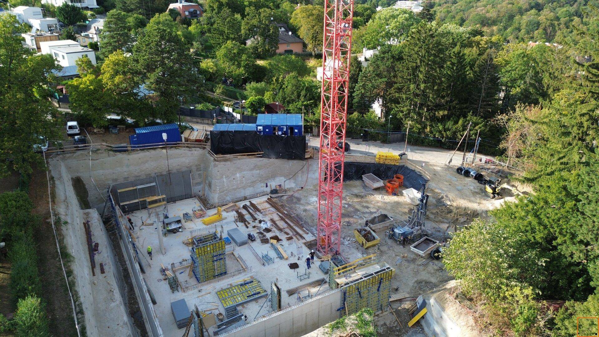 Detailansicht der Baustelle mit Fundamentarbeiten und Baugeräten in grüner Umgebung.