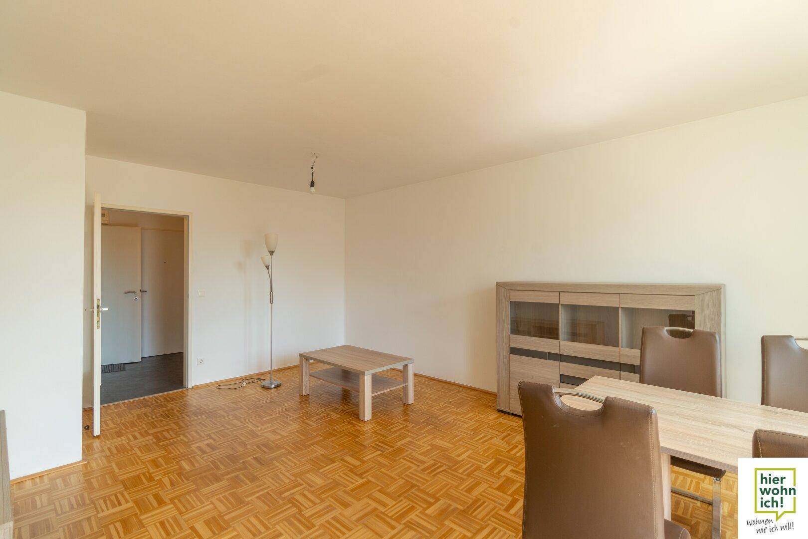 Heller Wohnbereich mit Fischgrätparkett und modernem Sideboard, bietet Zugang zu weiteren Räumen.