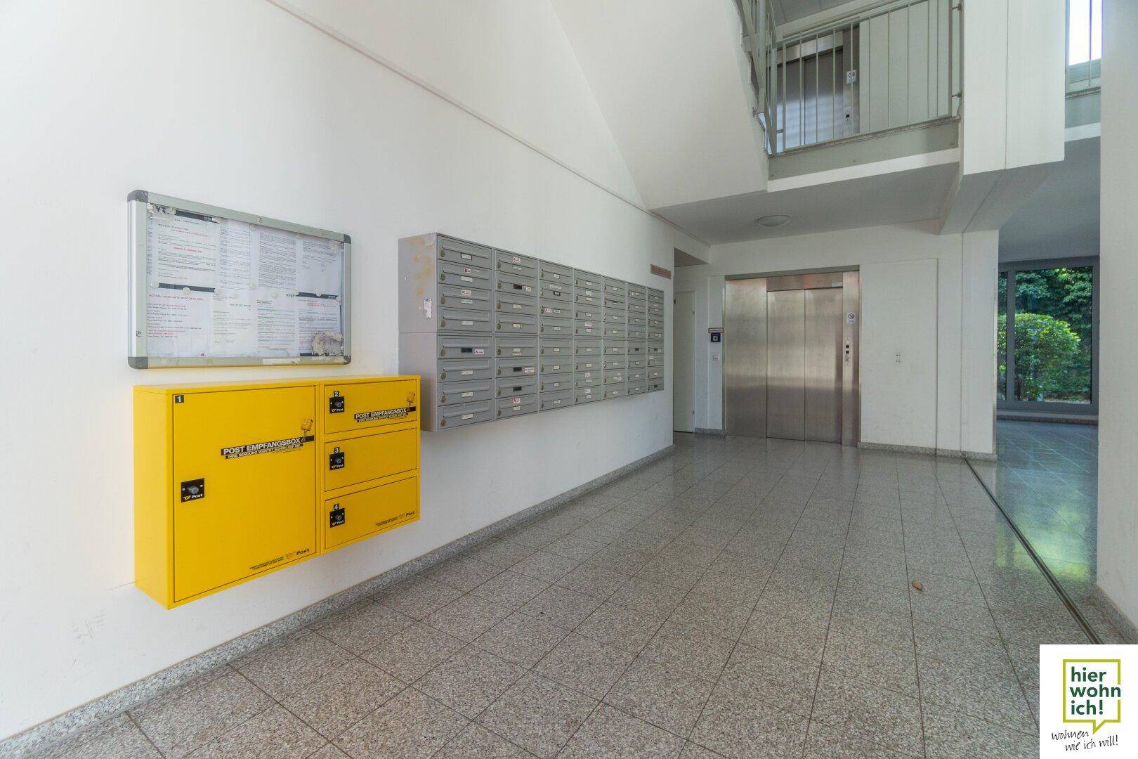 Eingangsbereich des Gebäudes mit Briefkästen, Aufzug und Treppenhaus, hell und geräumig.