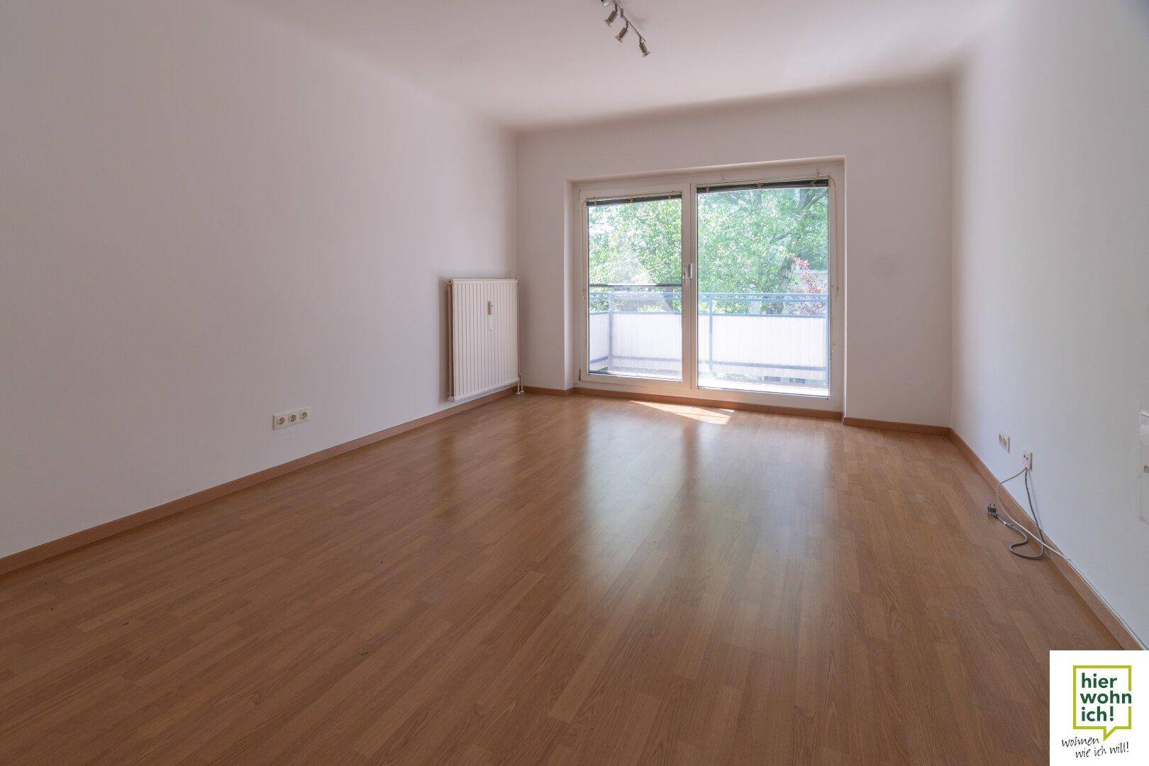 Helles Wohnzimmer mit Parkettboden und direktem Zugang zum sonnigen Balkon.